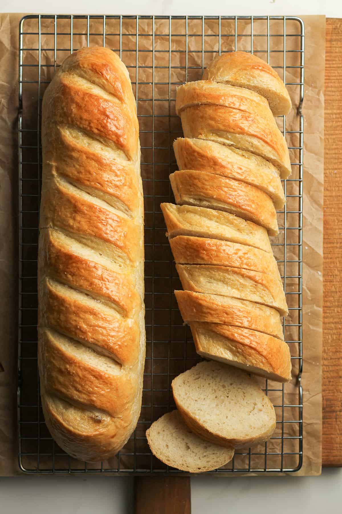 A large loaf of French bread beside a loaf of sliced bread.