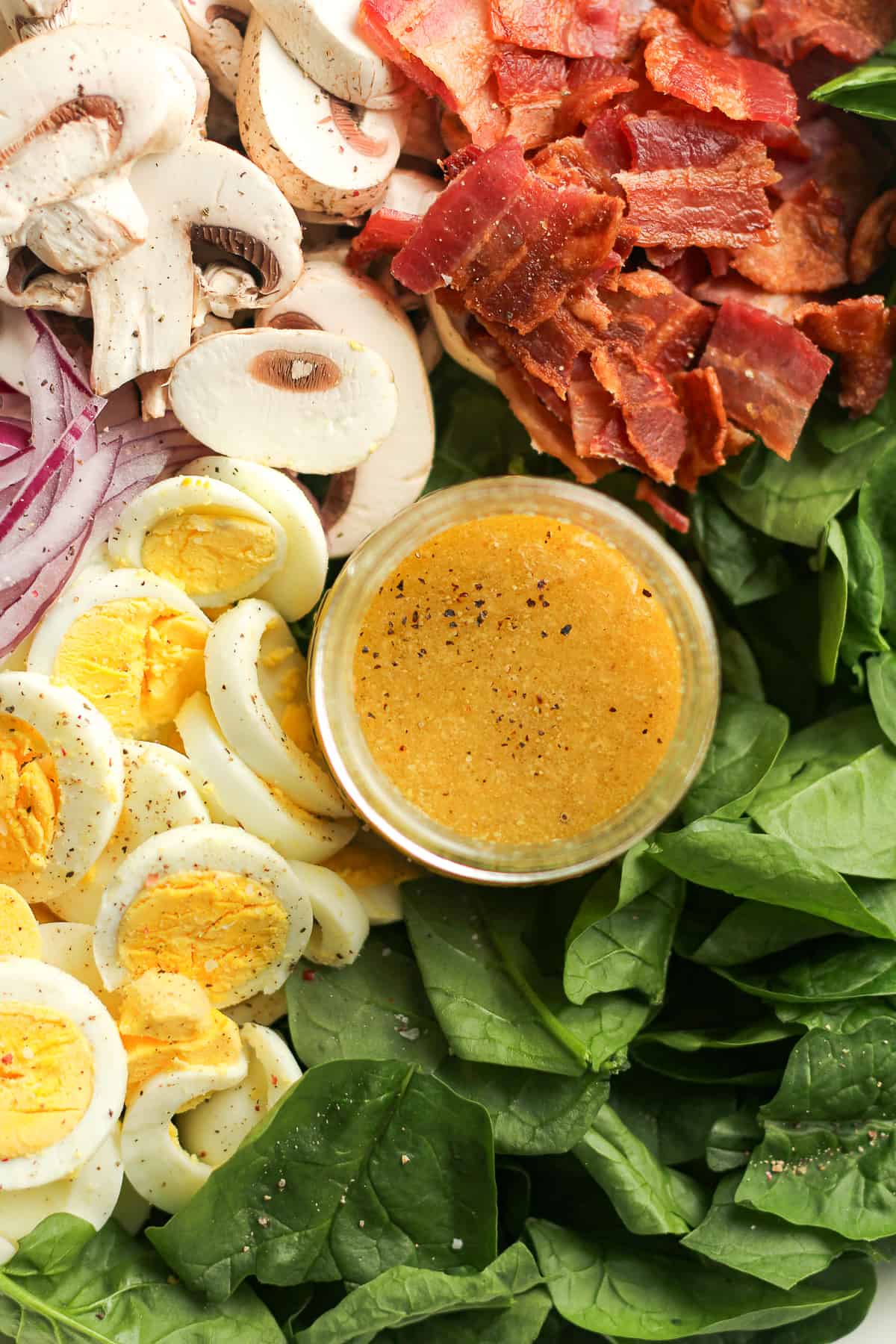 A closeup on the spinach salad dressing in a bowl of salad.