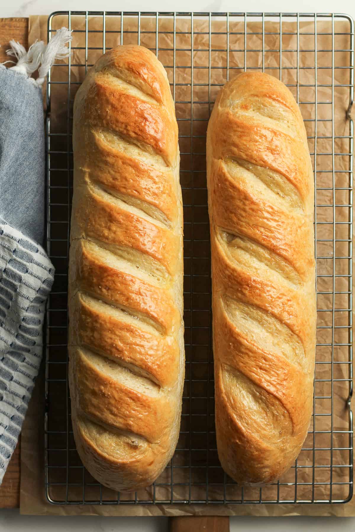 Two loaves of chewy French bread on a cooling rack.