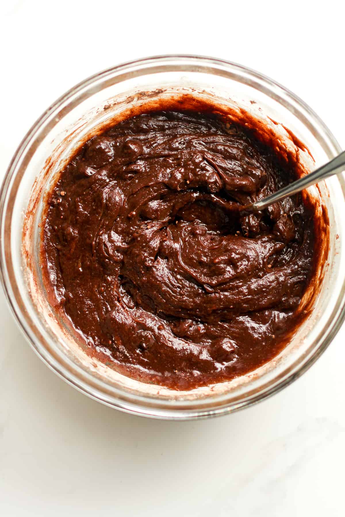 A bowl of the brownie batter with a spoon.