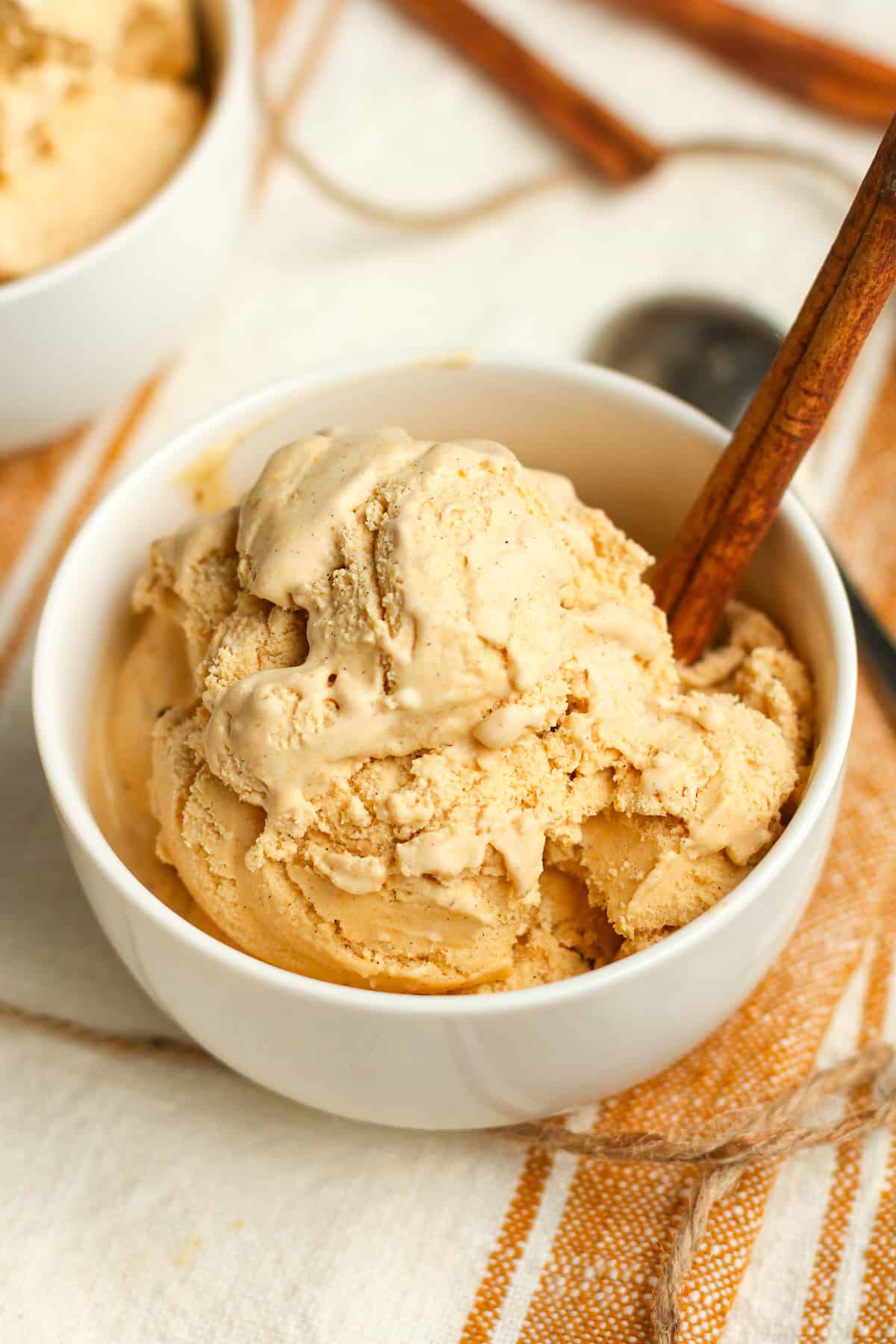 Side shot of a bowl of pumpkin ice cream with a cinnamon stick.