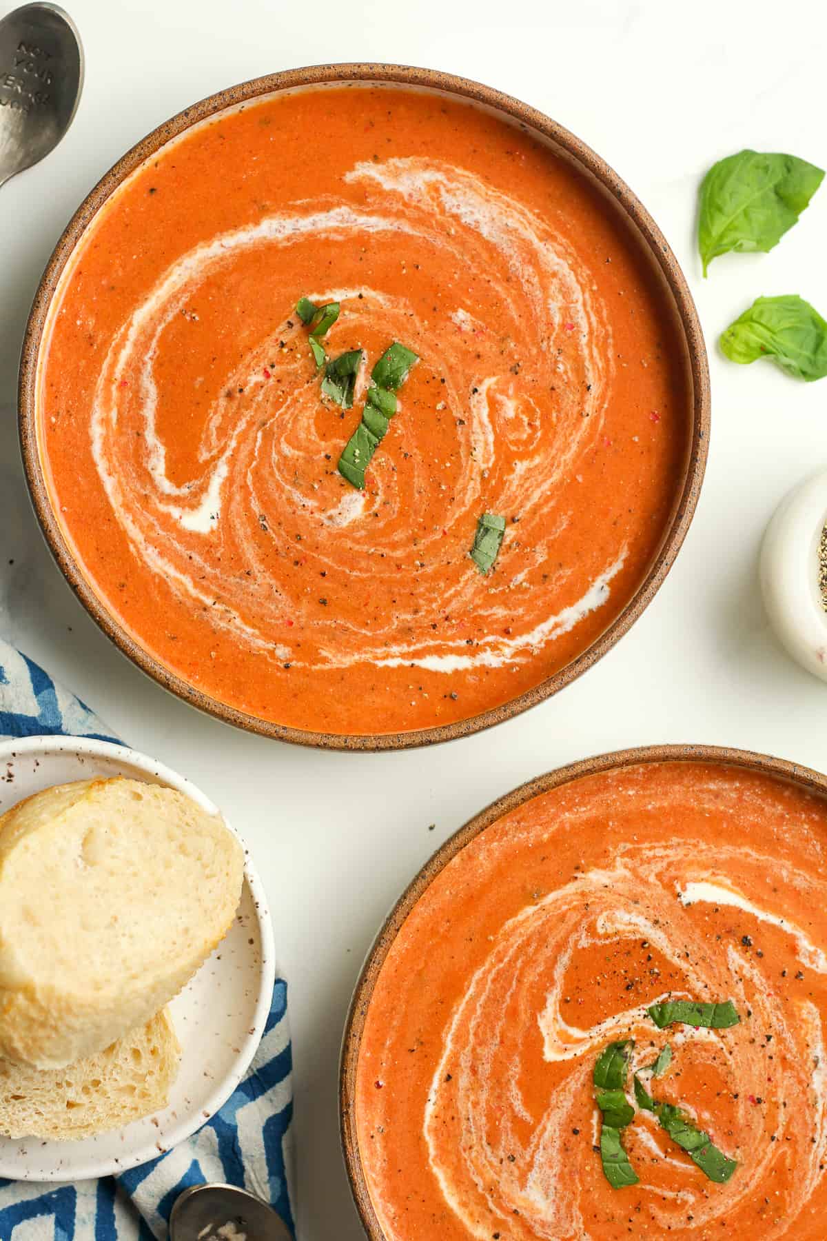Two bowls of tomato bisque with swirls of cream.