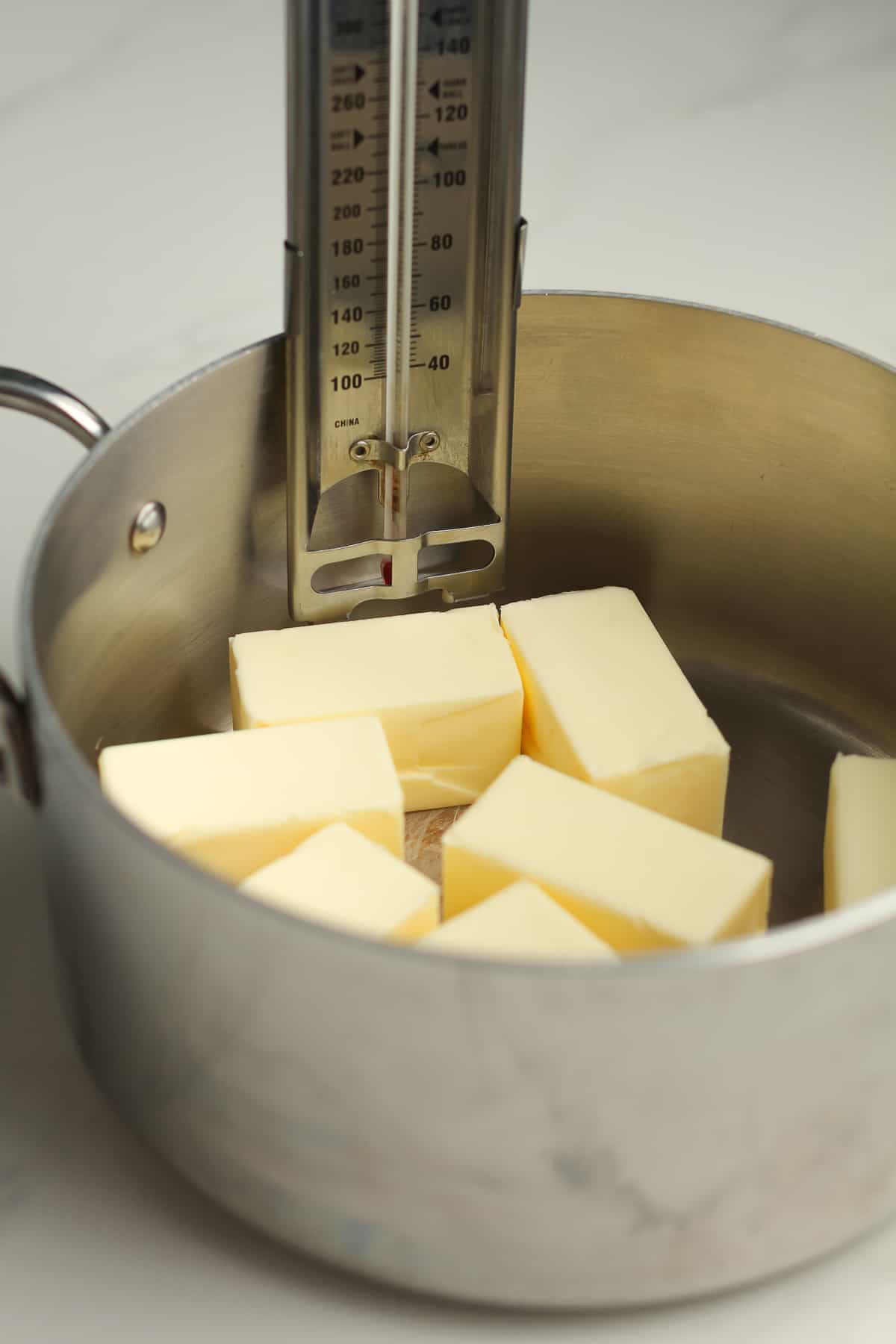 The butter in a sauce pan with a candy thermometer attached to the side of the pan.