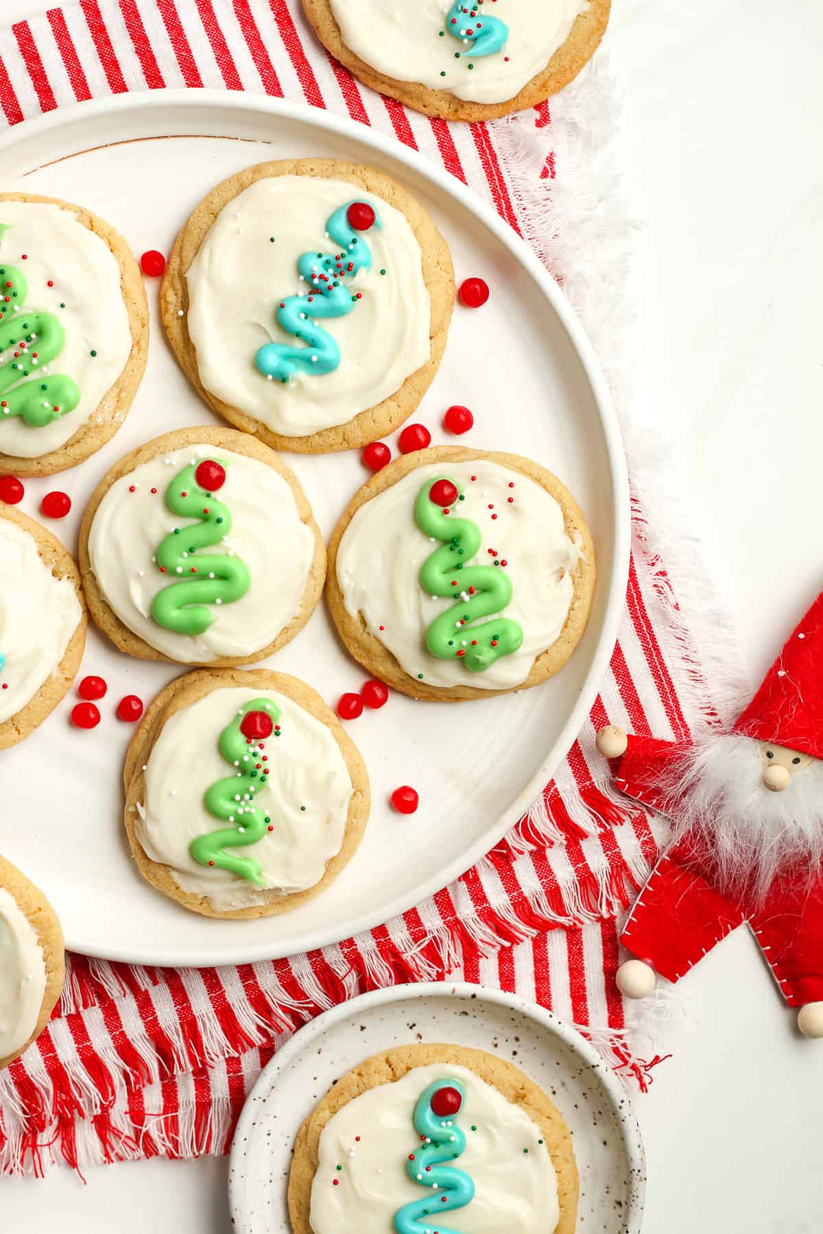A partial plate of frosted sugar cookies with mini Christmas trees.