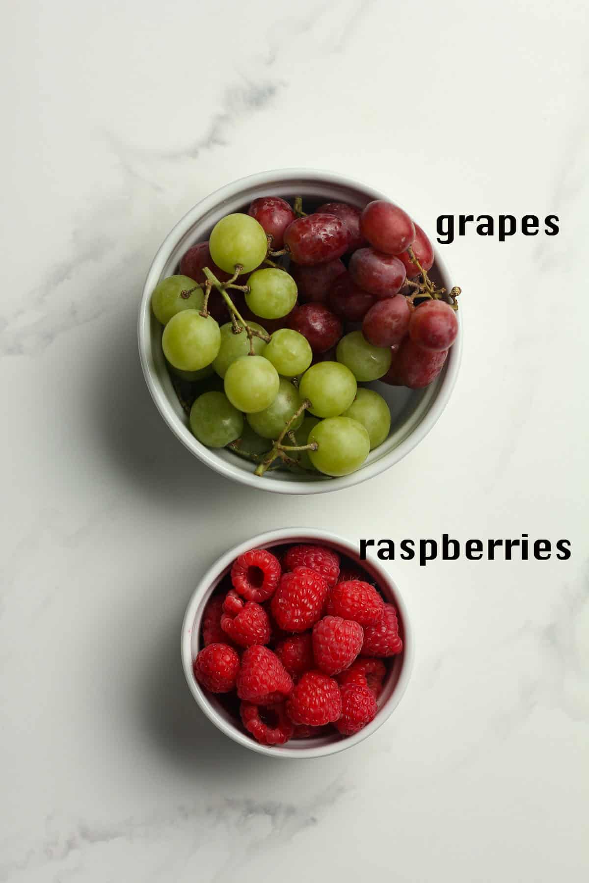 Bowls of grapes and raspberries.