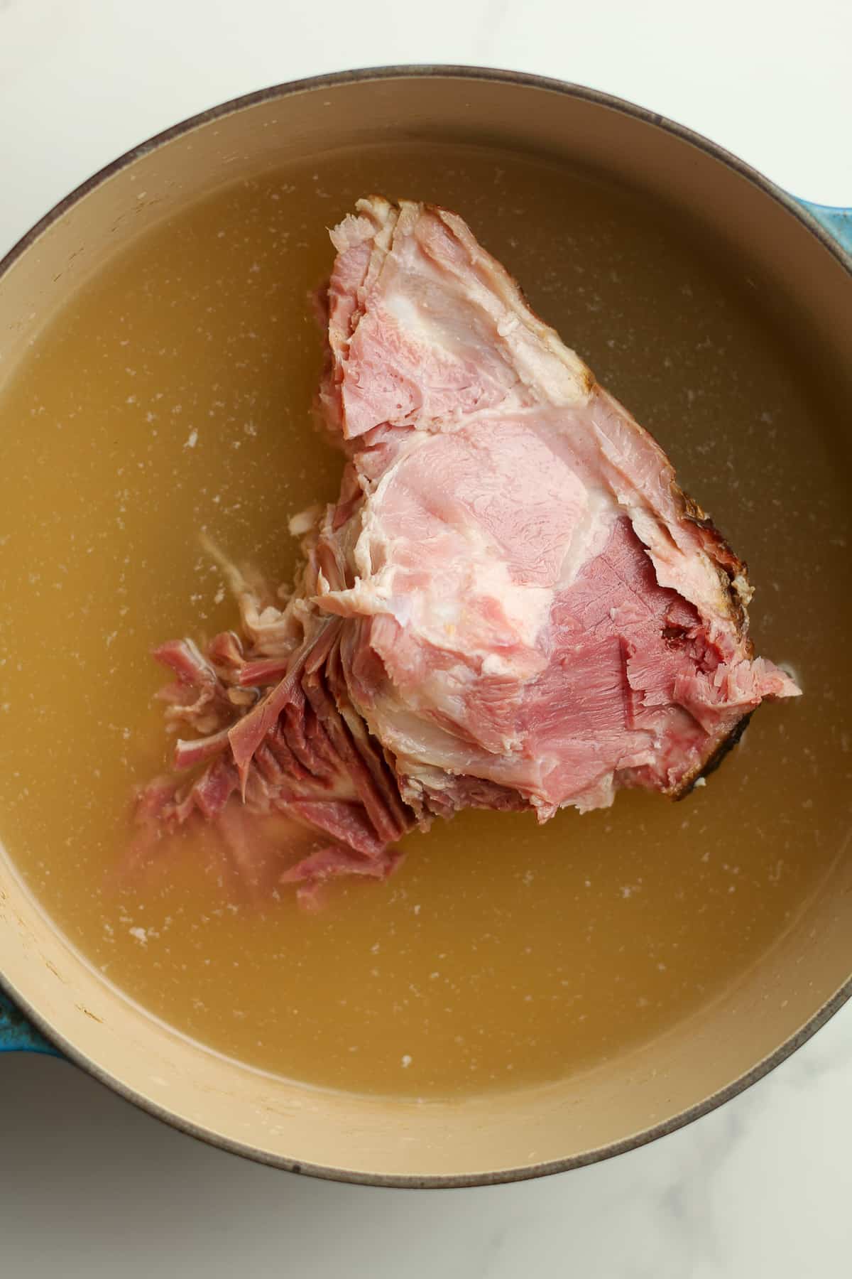 A pot of broth with a ham bone inside.