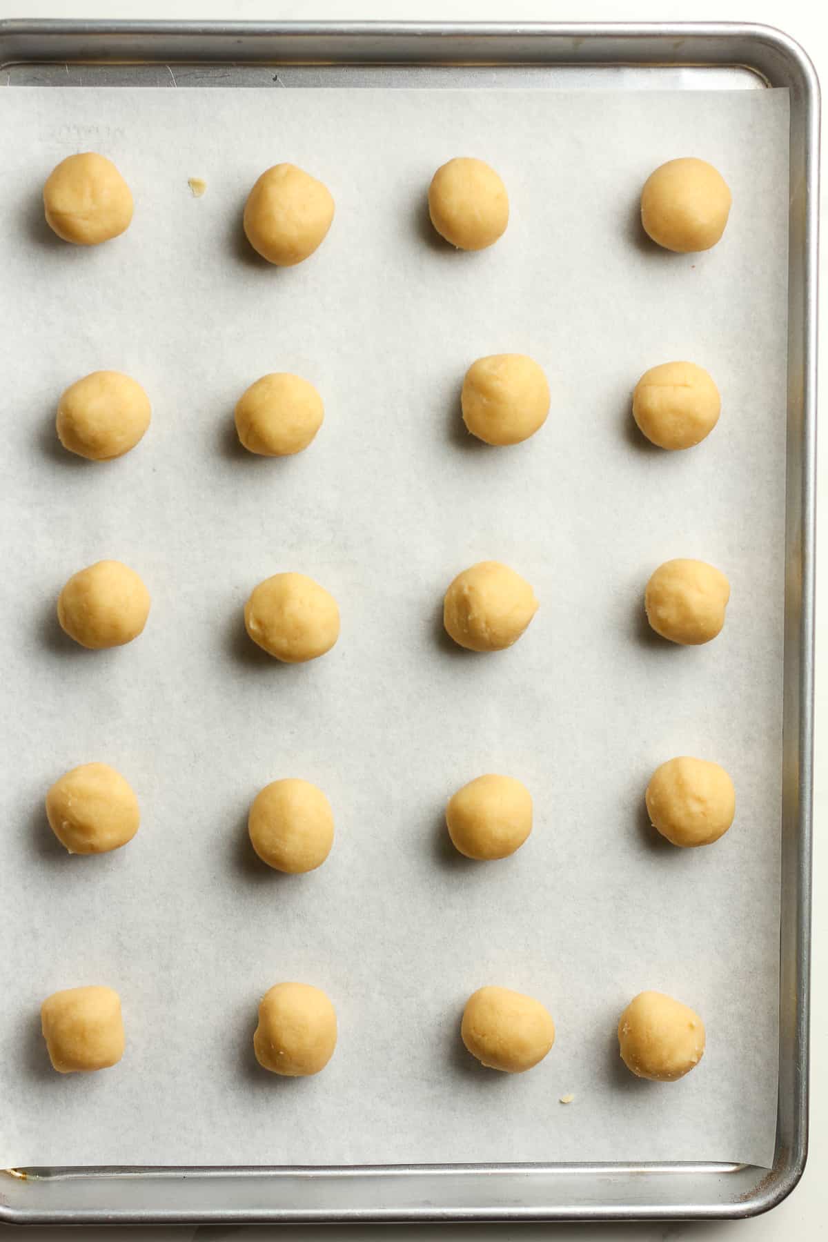 A baking sheet with 20 one-inch balls spread out evenly.