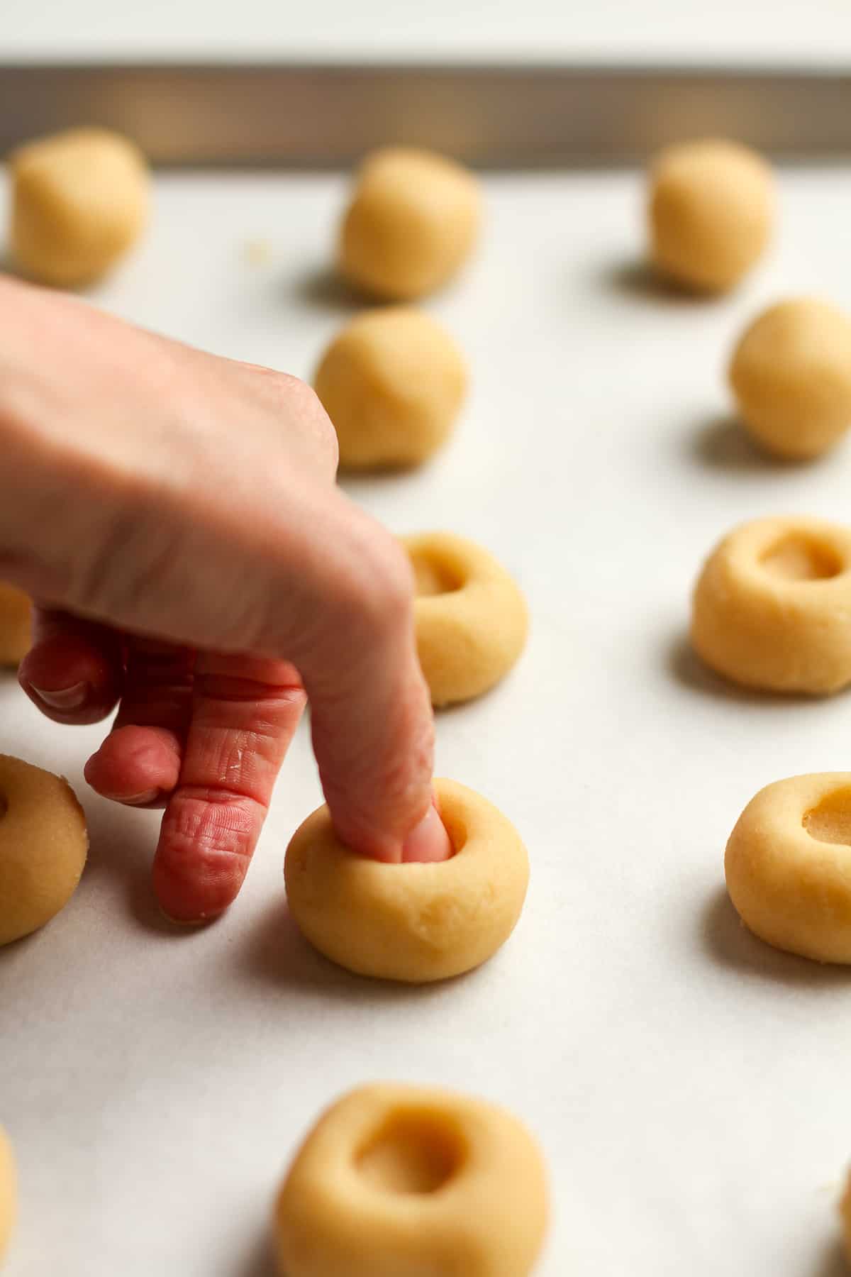 Side view of a thumb making an indention in the cookies.