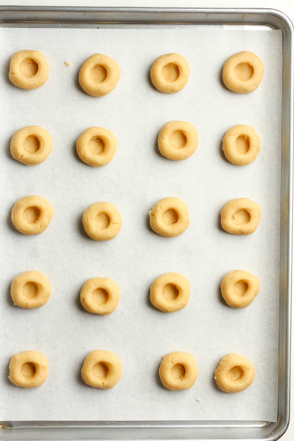 A sheet pan of the thumbprint cookies before preserves added.