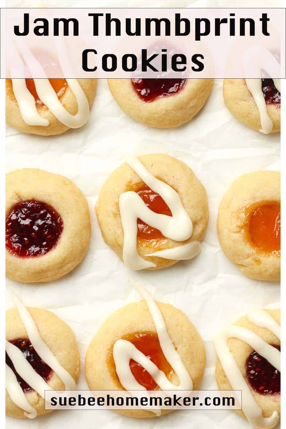 Several jam thumbprint cookies on white parchment paper.