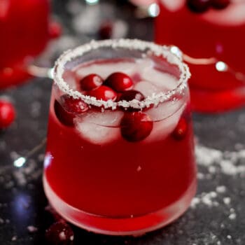 Closeup on a salt-rimmed glass of mistletoe cranberry margaritas.