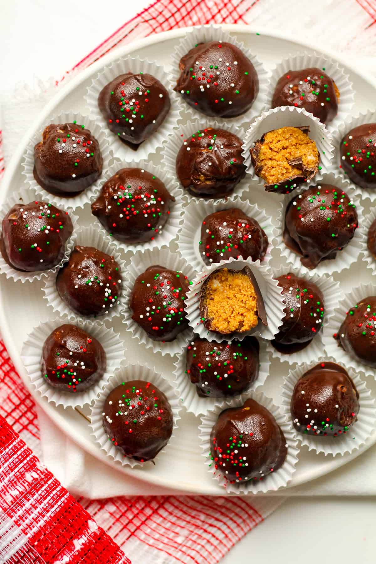 A plate of no bake peanut butter balls with two partial balls.