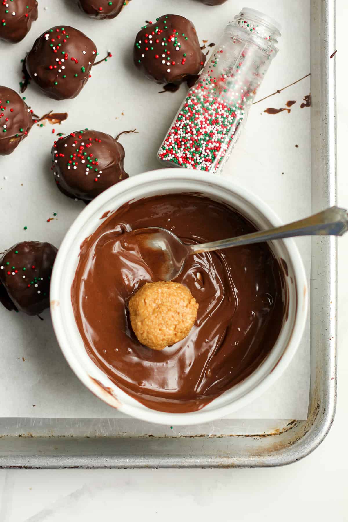 A bowl of the melted chocolate with a peanut butter ball inside.