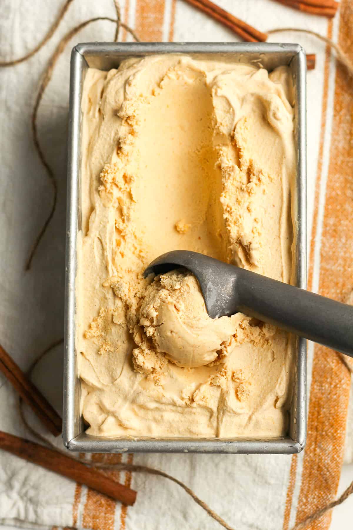 A pan of pumpkin ice cream, with a scoop inside the pan.