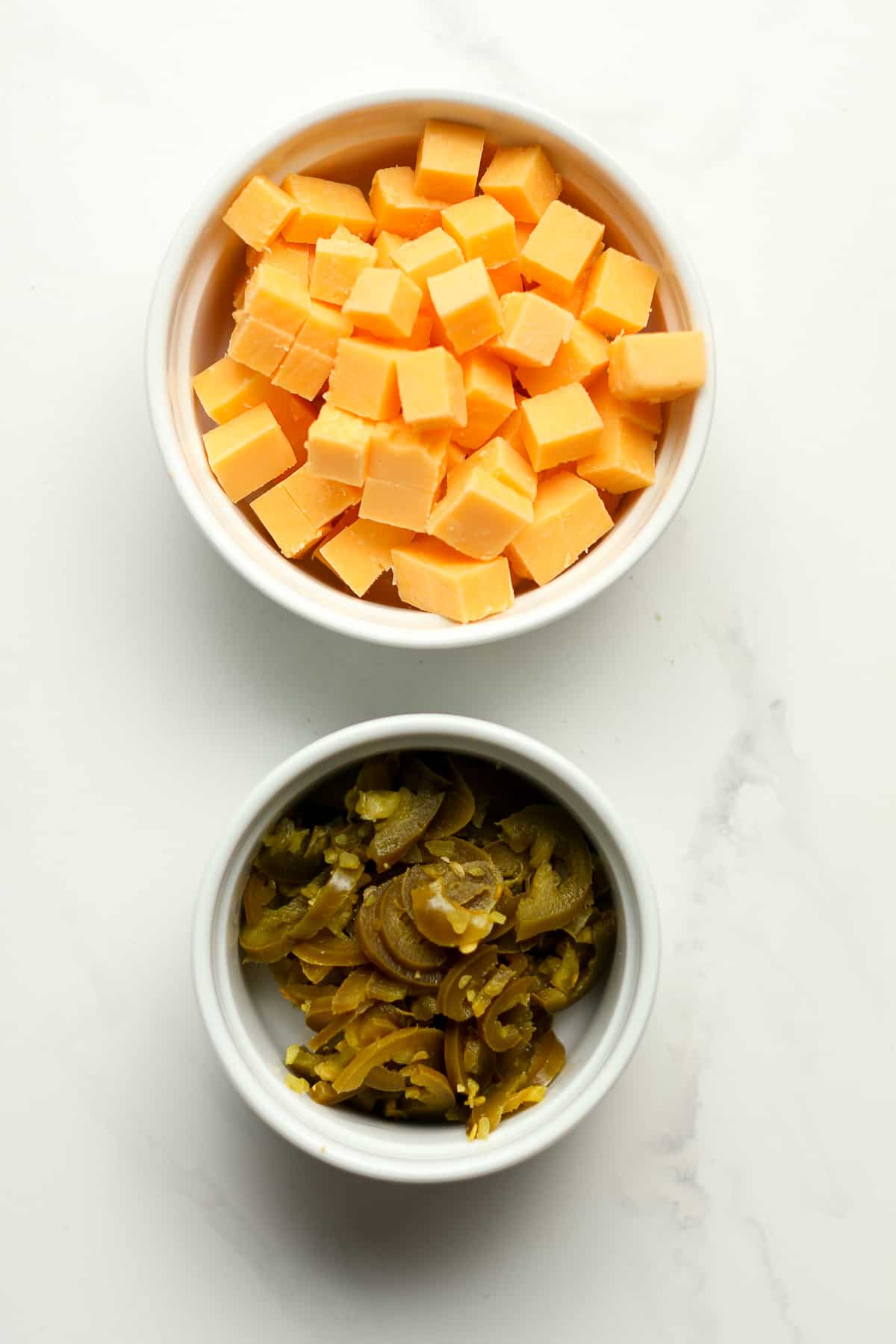 Bowls of cheddar cubes and jalapeño slices.