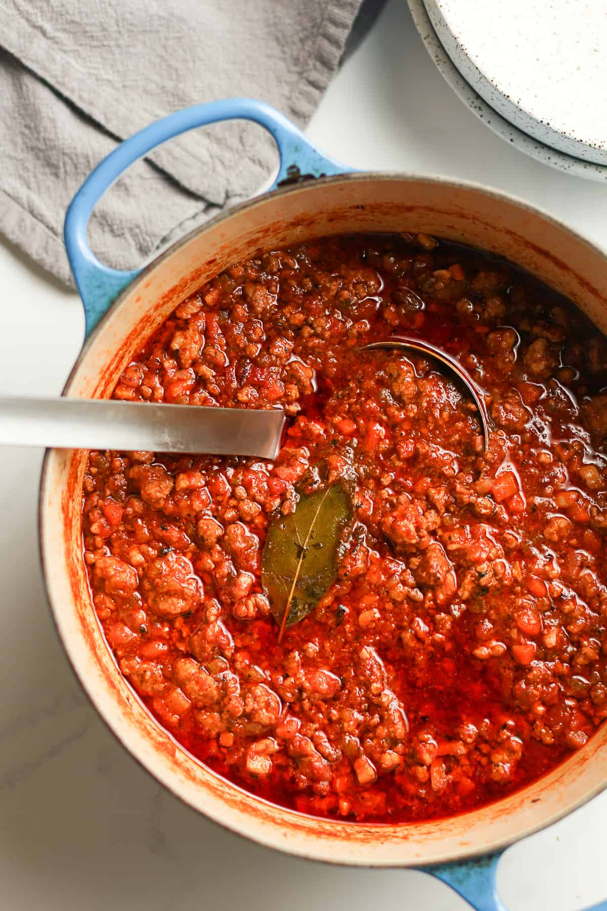 A stock pot of bolognese with a soup ladle.