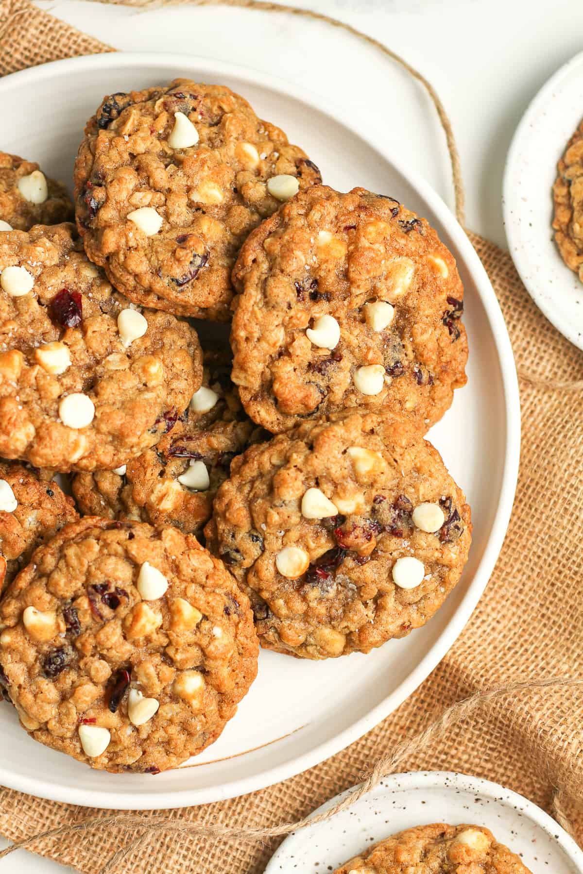 A portion of a plate of baked white chocolate oatmeal cookies with cranberries.
