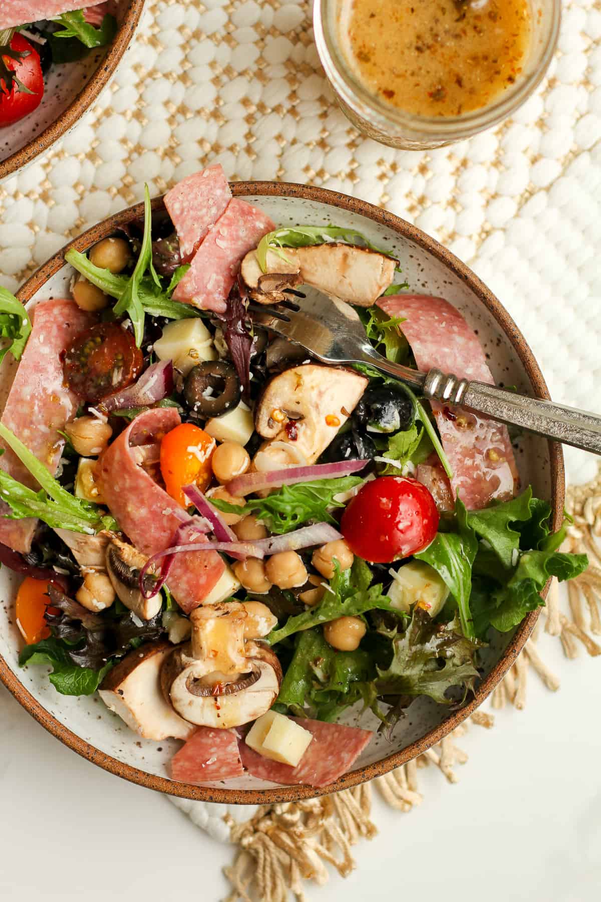 A closeup on a salad with salami, cheese and olives.