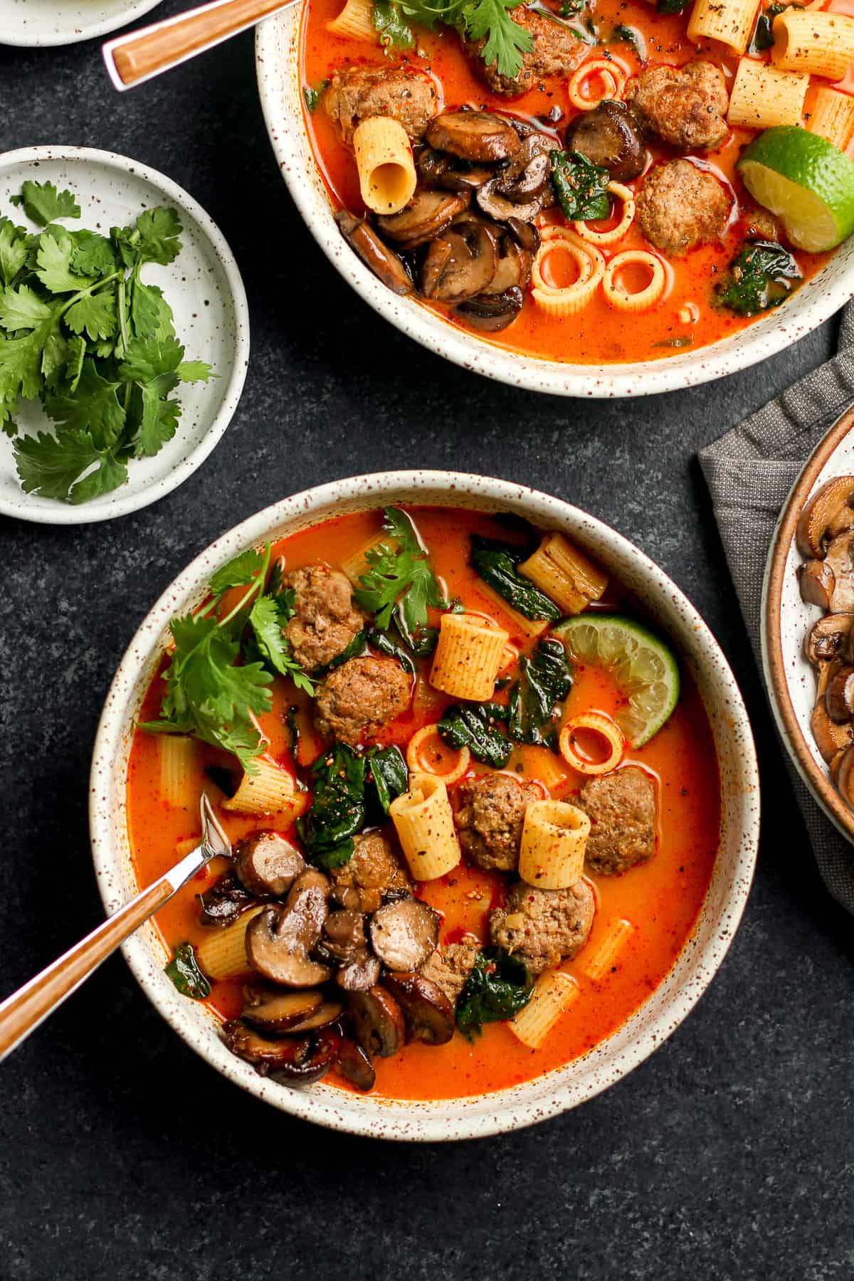 Two bowls of Thai meatball soup with noddles and mushrooms.