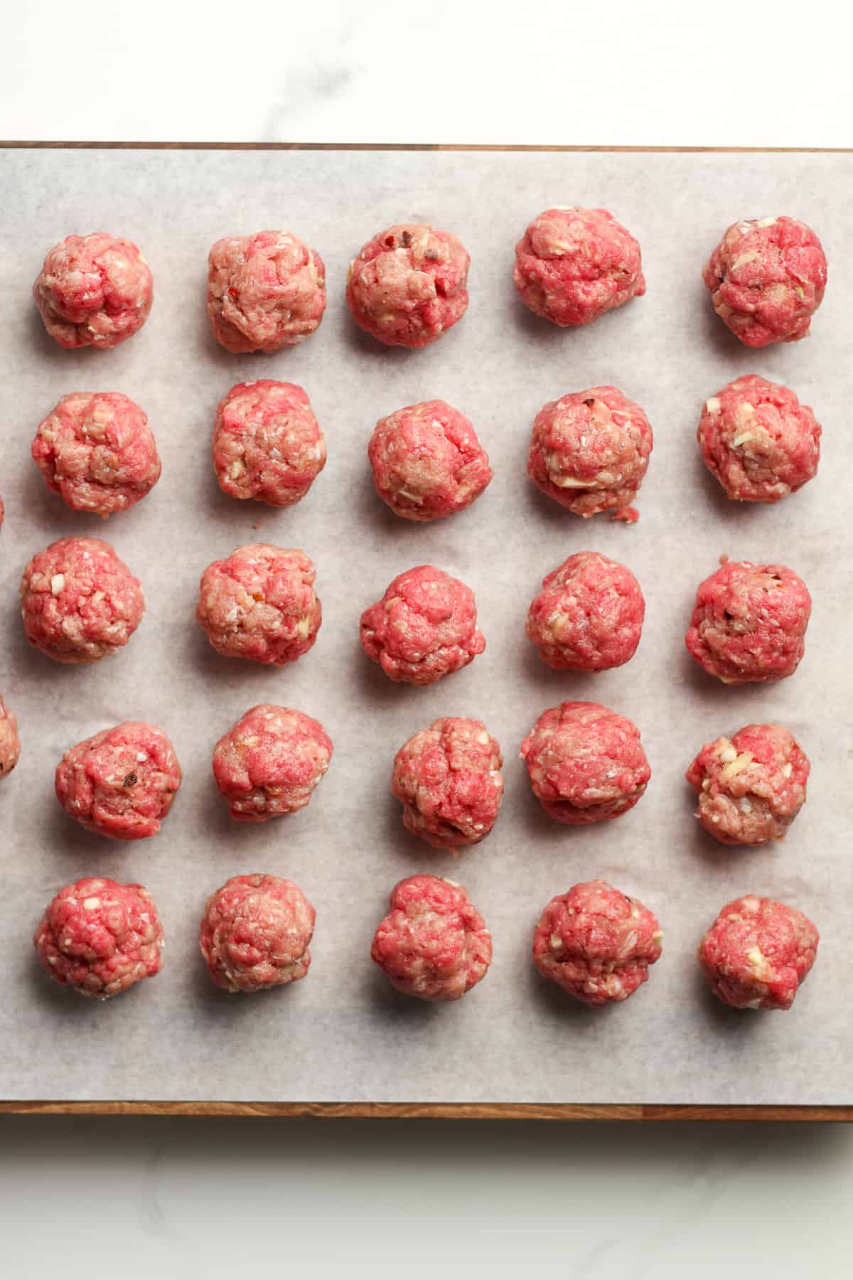 37 small meatballs on white parchment paper.