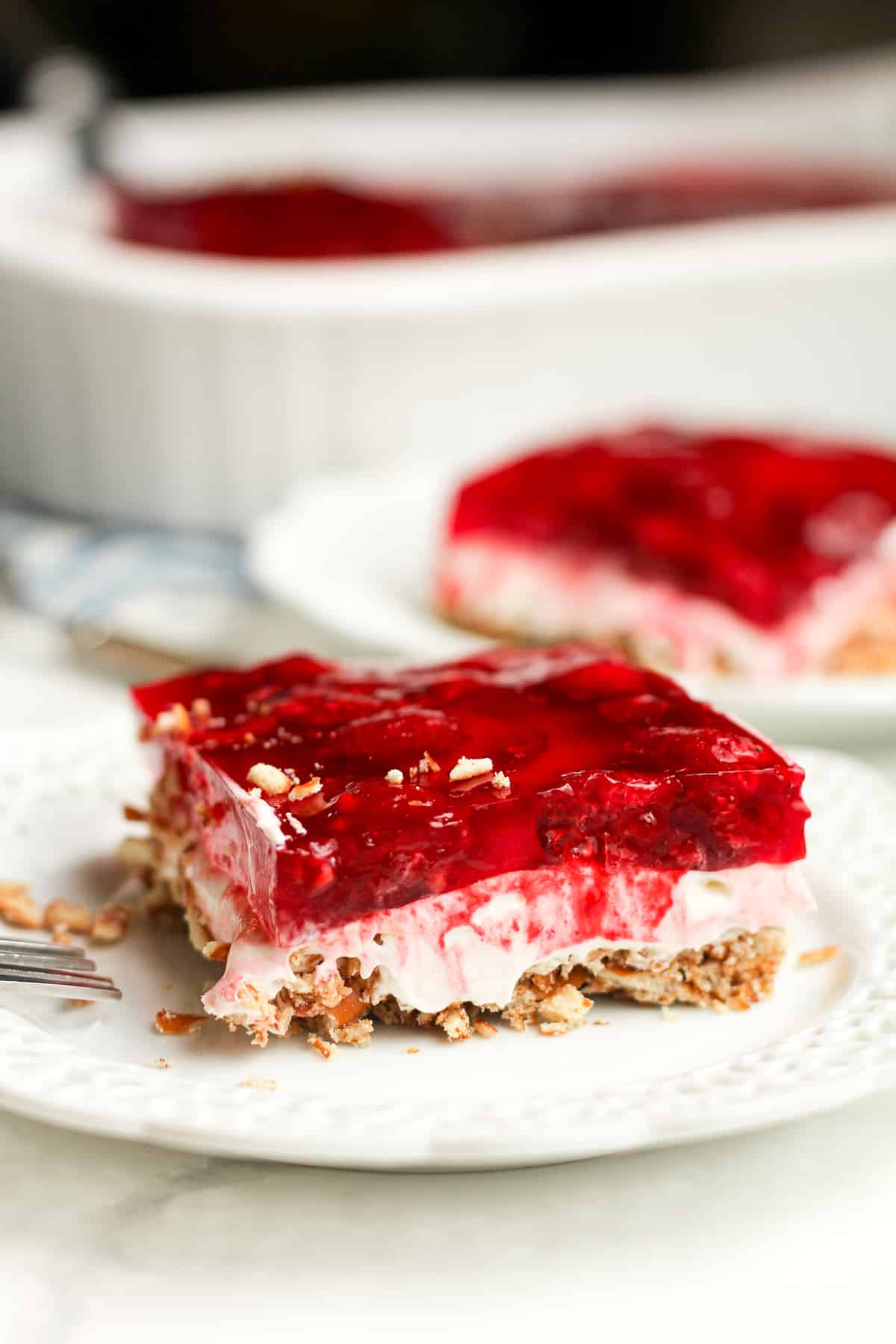 Side shot of two pieces of raspberry jello salad with pretzels.