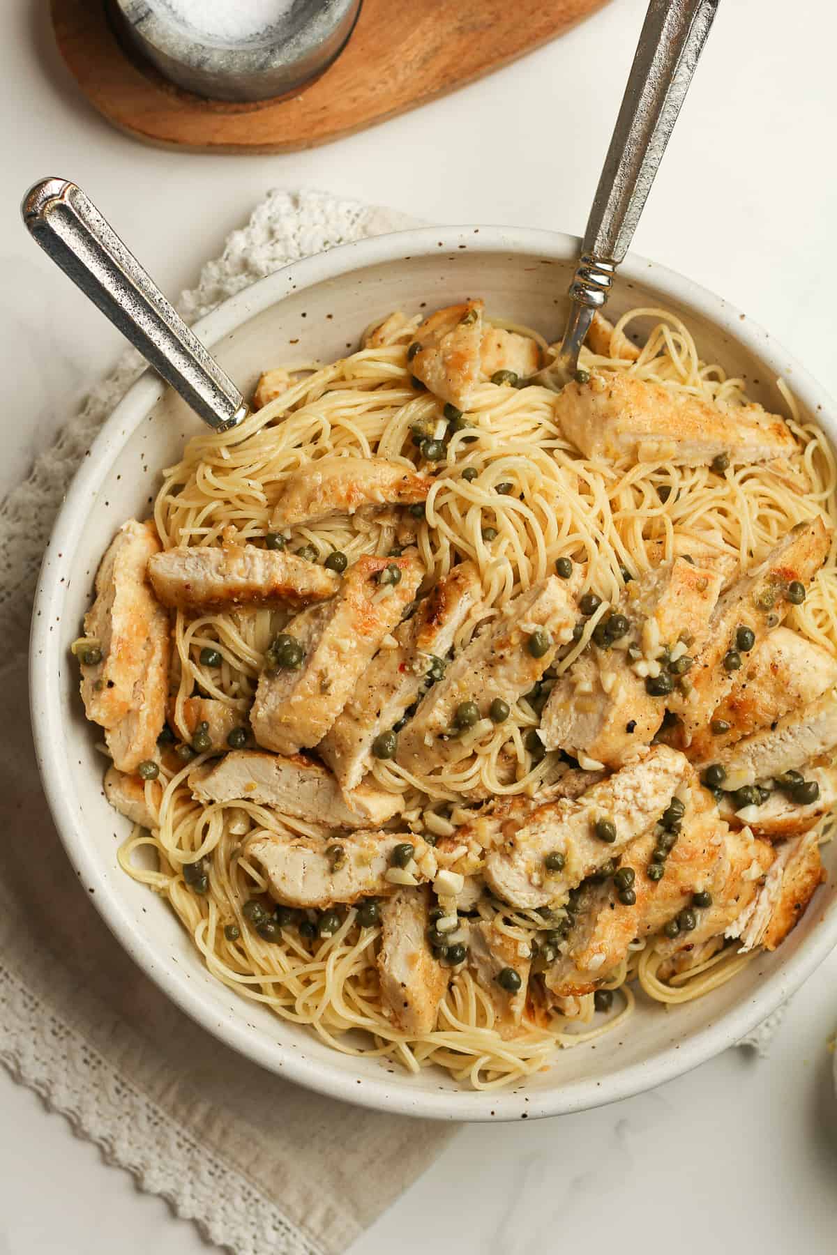 A bowl of the chicken piccata with two forks.