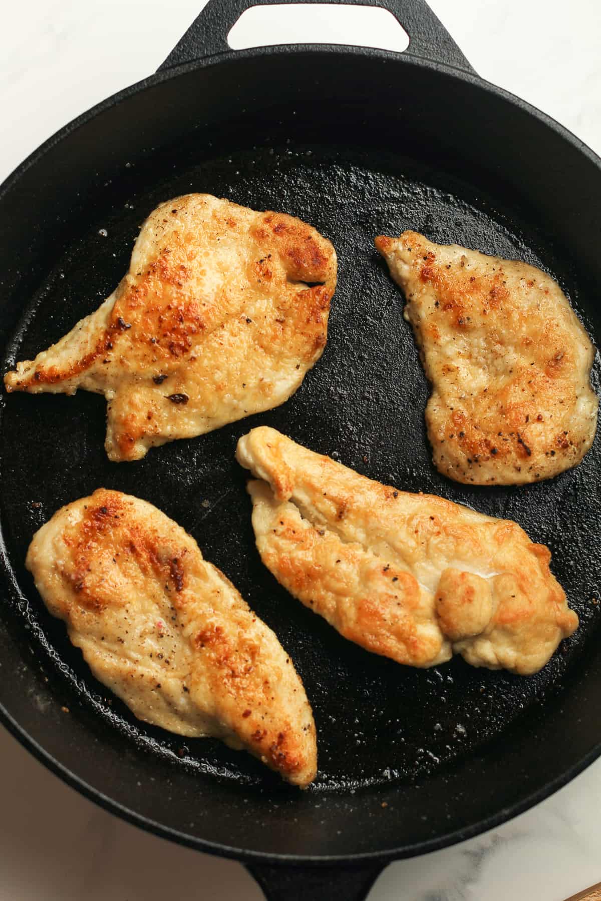 A skillet of the browned chicken breasts.