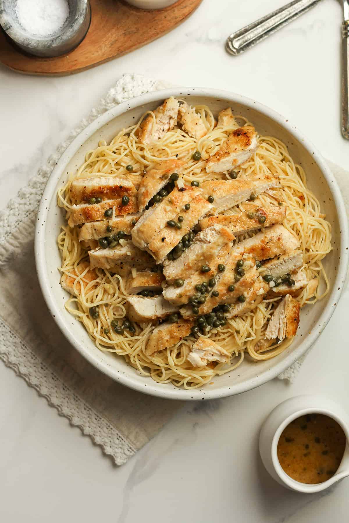 A bowl of the chicken piccata over pasta.