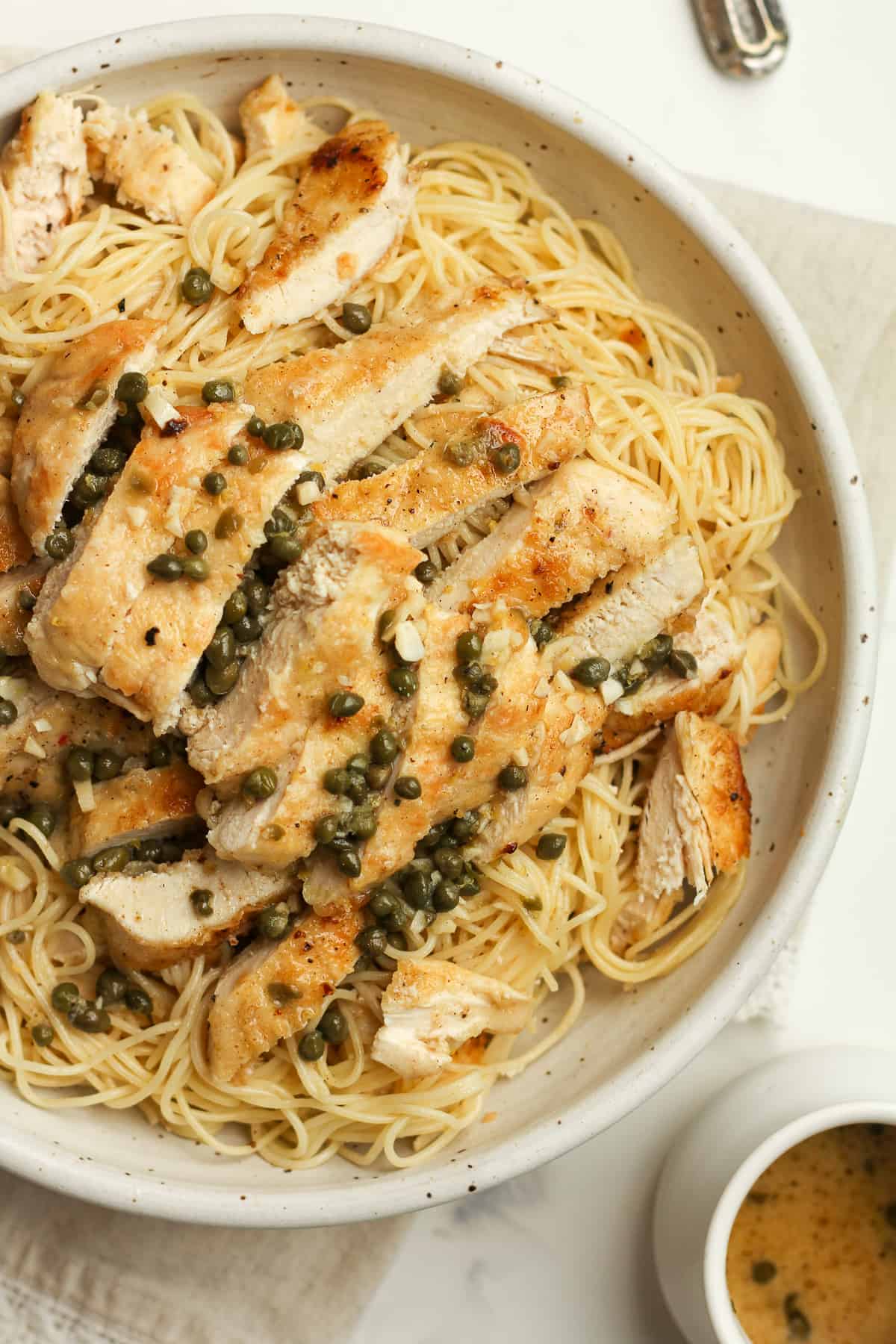 Closeup on a bowl of pasta with chicken piccata.