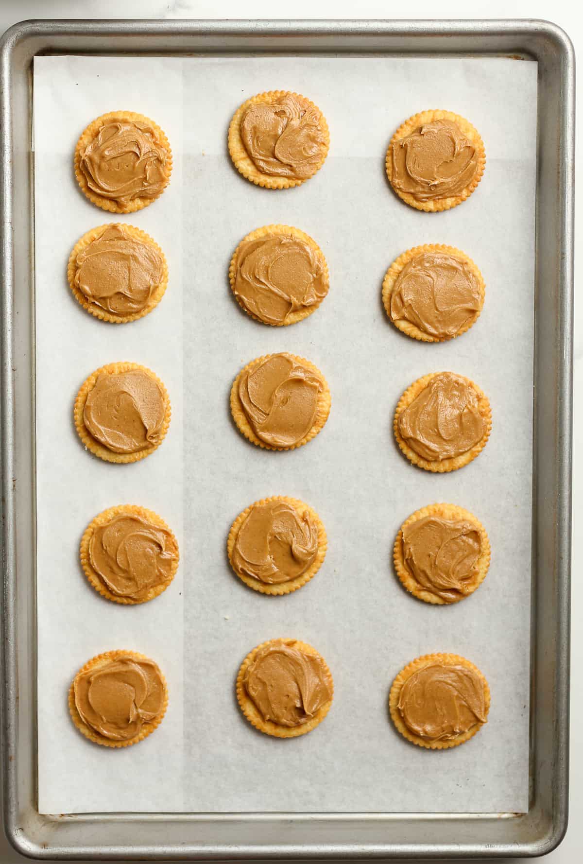 A pan with Ritz crackers and peanut butter on top.