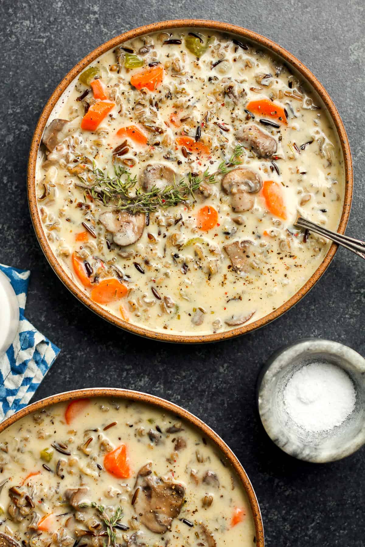 Two bowls of creamy wild rice soup, with thyme on top.