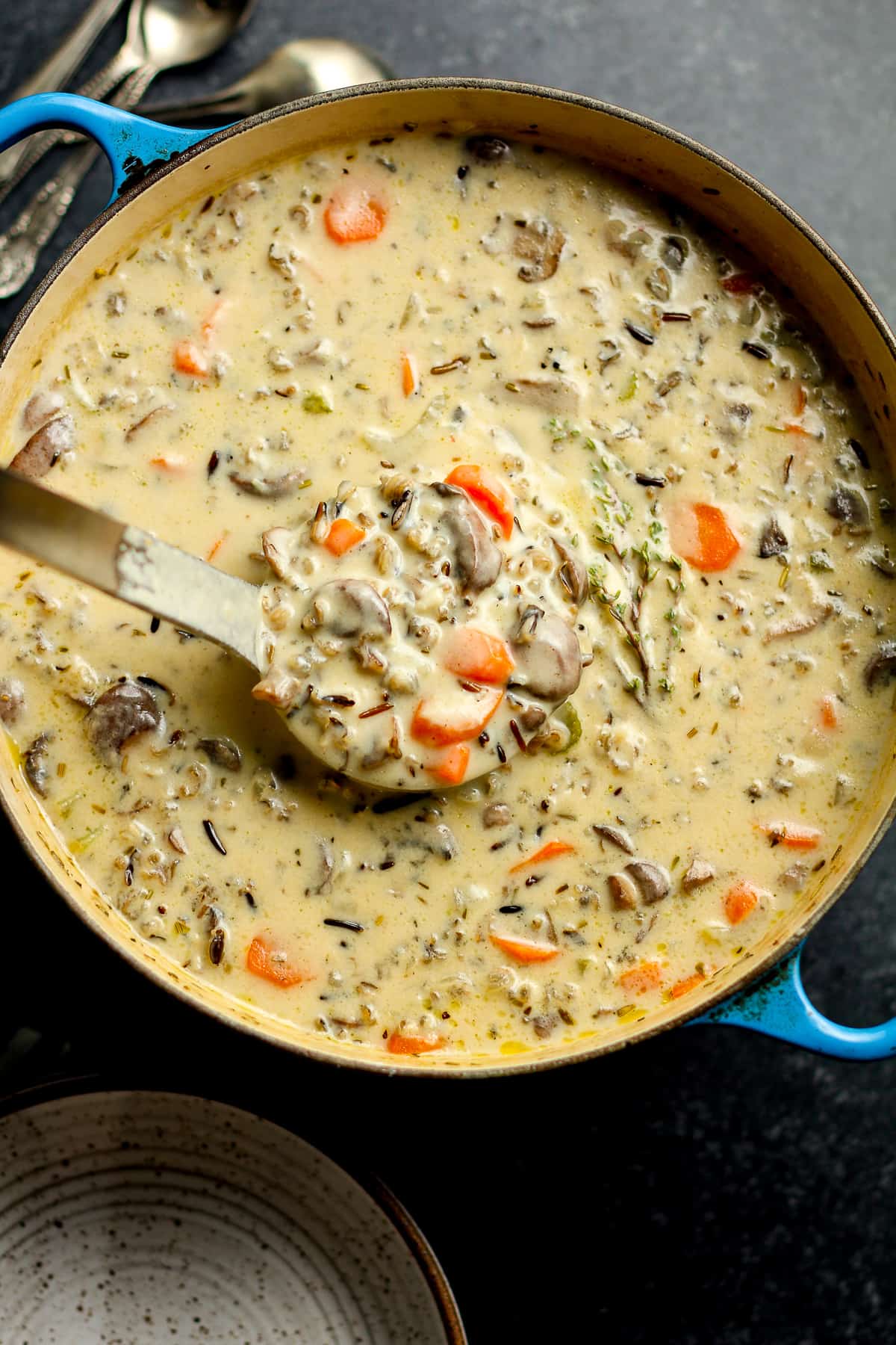 A pot of creamy mushroom wild rice soup with a soup ladle.