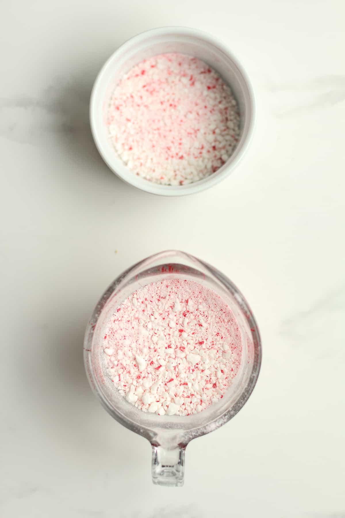 A measuring cup of crushed peppermint and a small bowl of reserved peppermint.