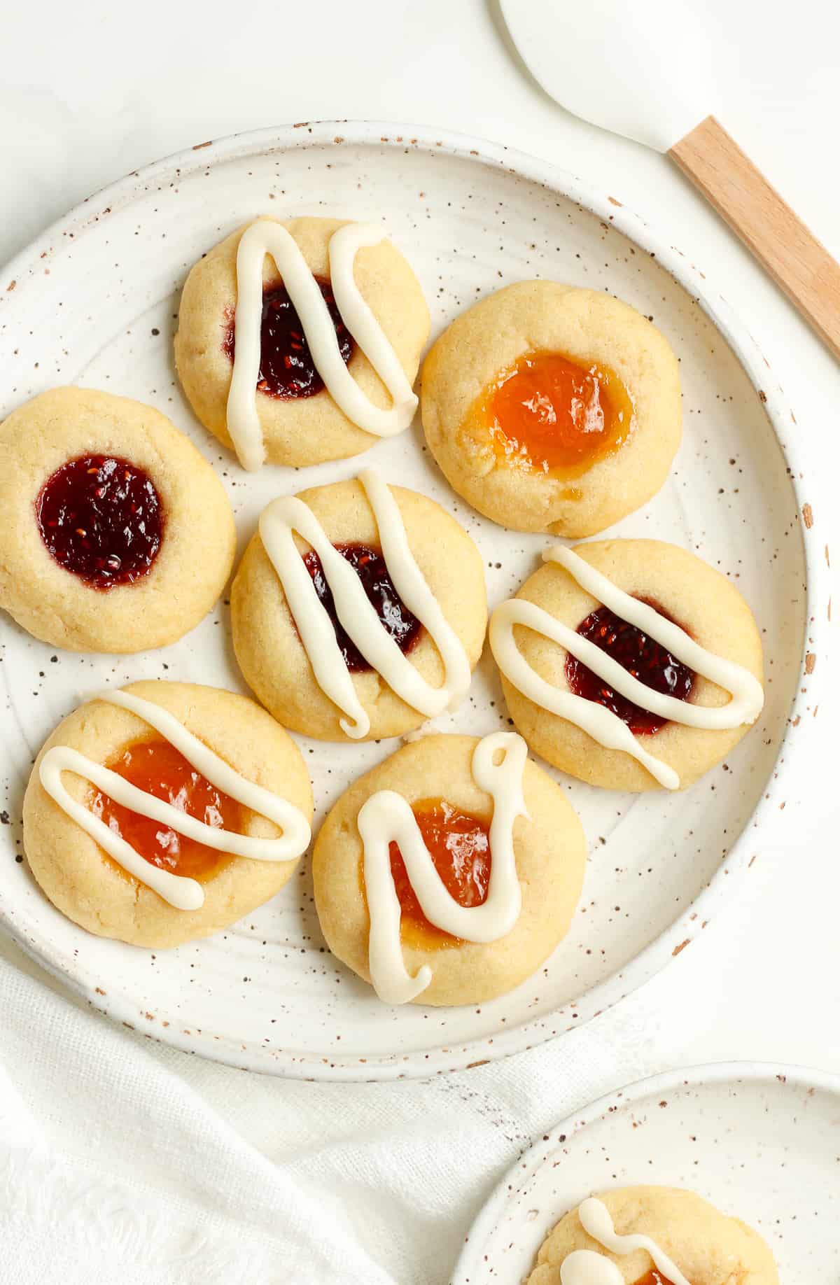 A plate of jam thumbprint cookies with drizzle.
