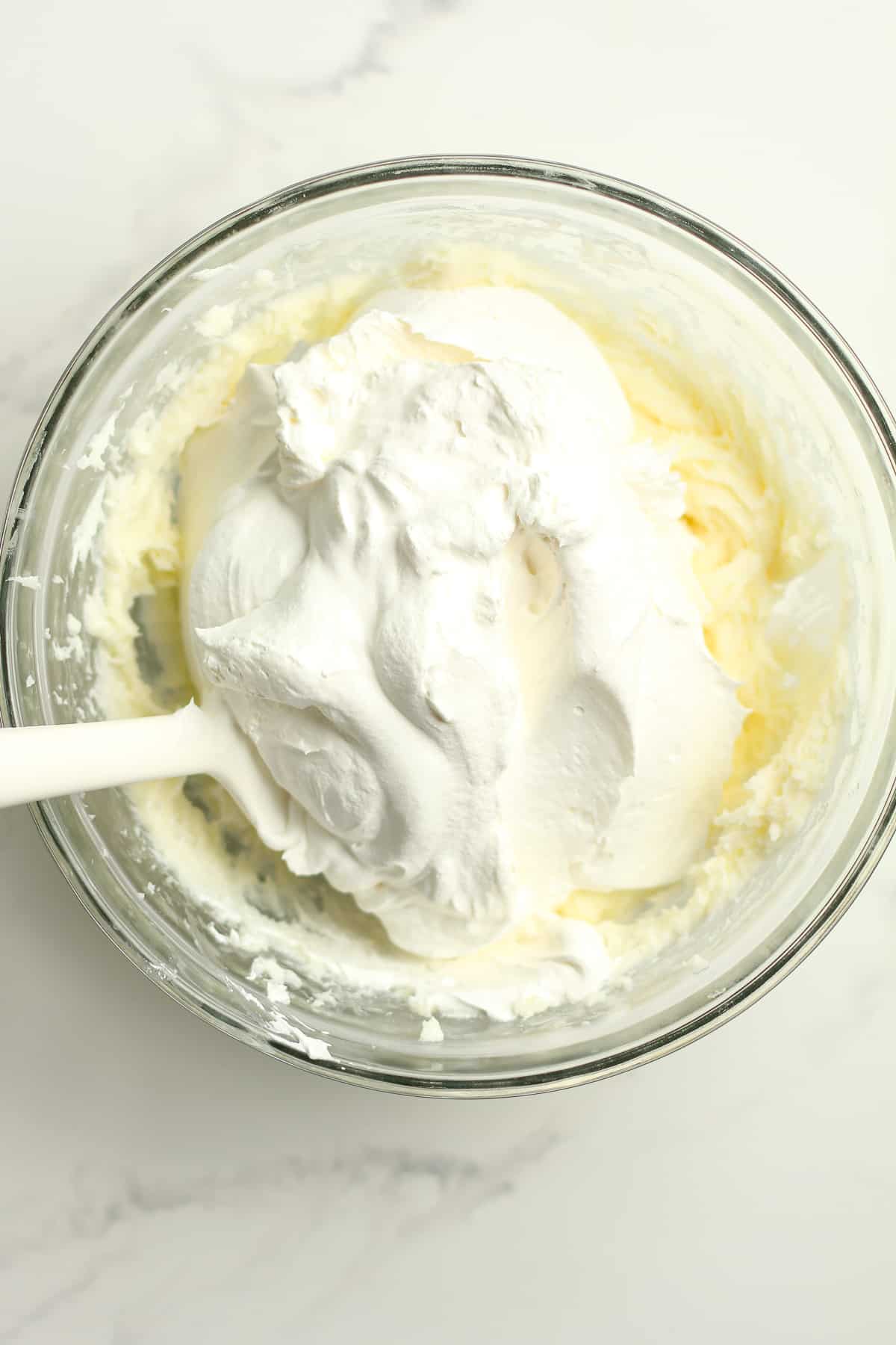 A bowl of the cream cheese mixture with the Cool Whip on top.