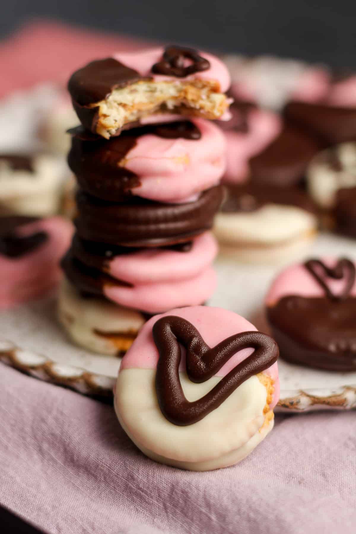 A stack of ritz cookies with one in front of it decorated with a heart.