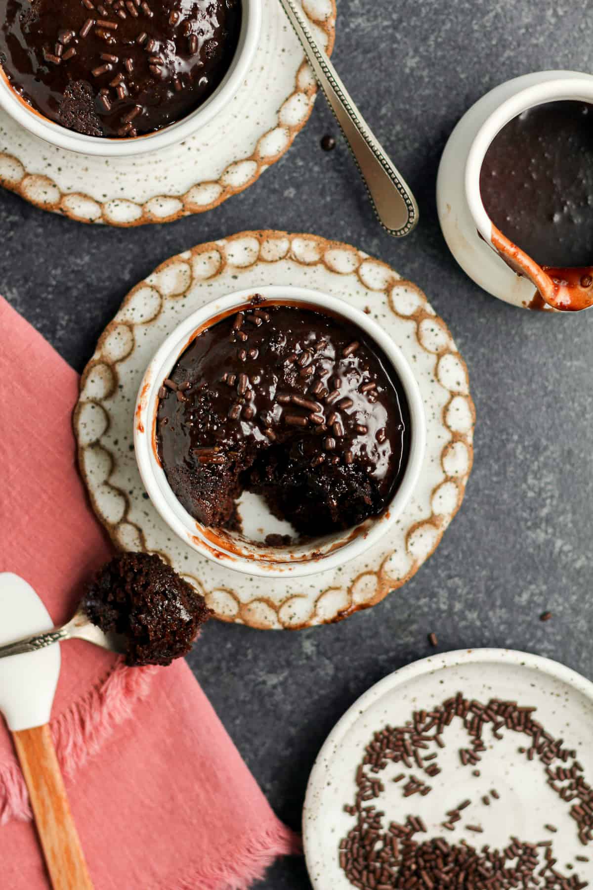 Two ramekins of chocolate cake for two, with a pink napkin.