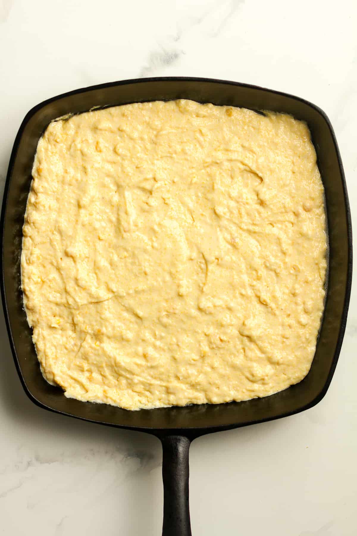 A square skillet with the cornbread batter.