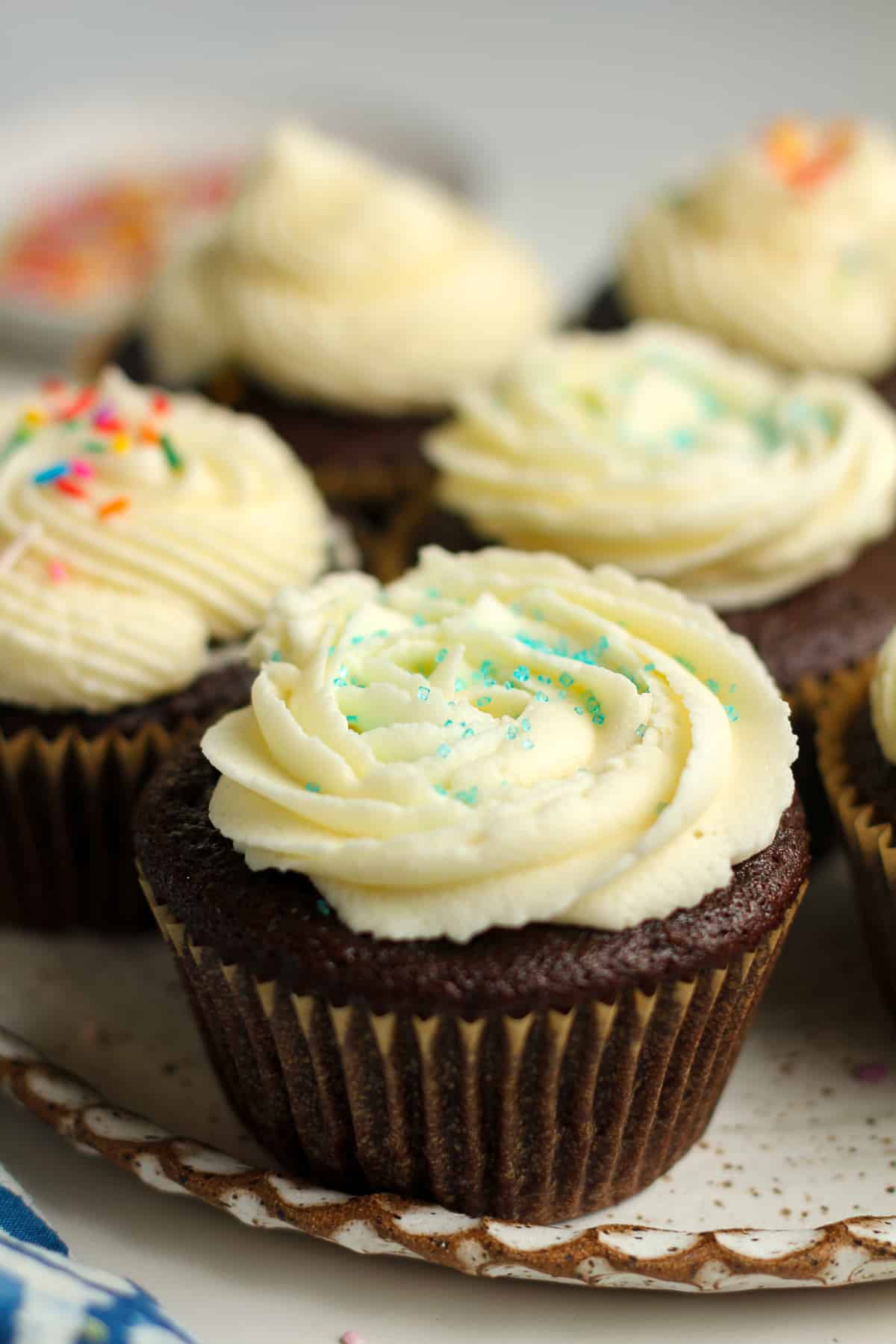 Side view of a plate of chocolate cupcakes with vanilla buttercream.