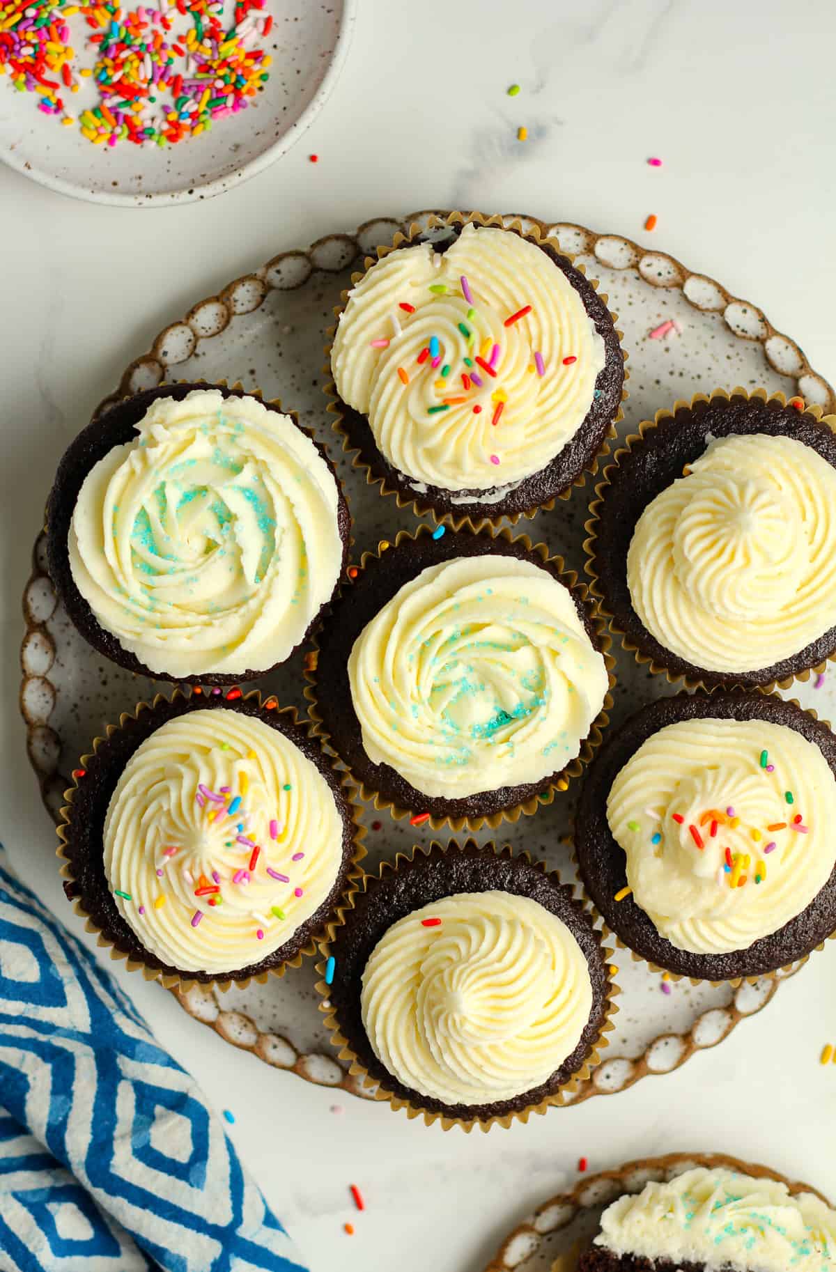 Overhead shot of a plate of jumbo chocolate cupcakes with sprinkles.