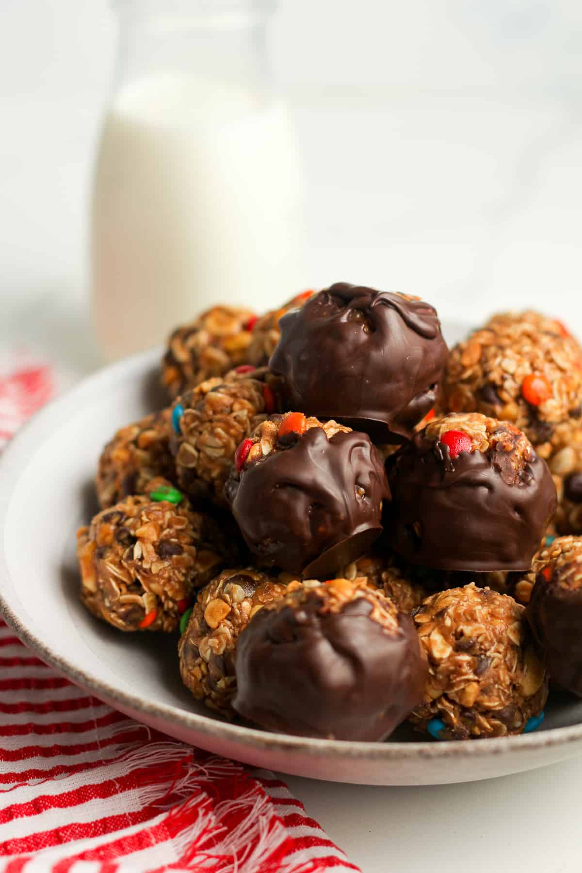 Side shot of a bowl of monster cookie balls, some with chocolate.