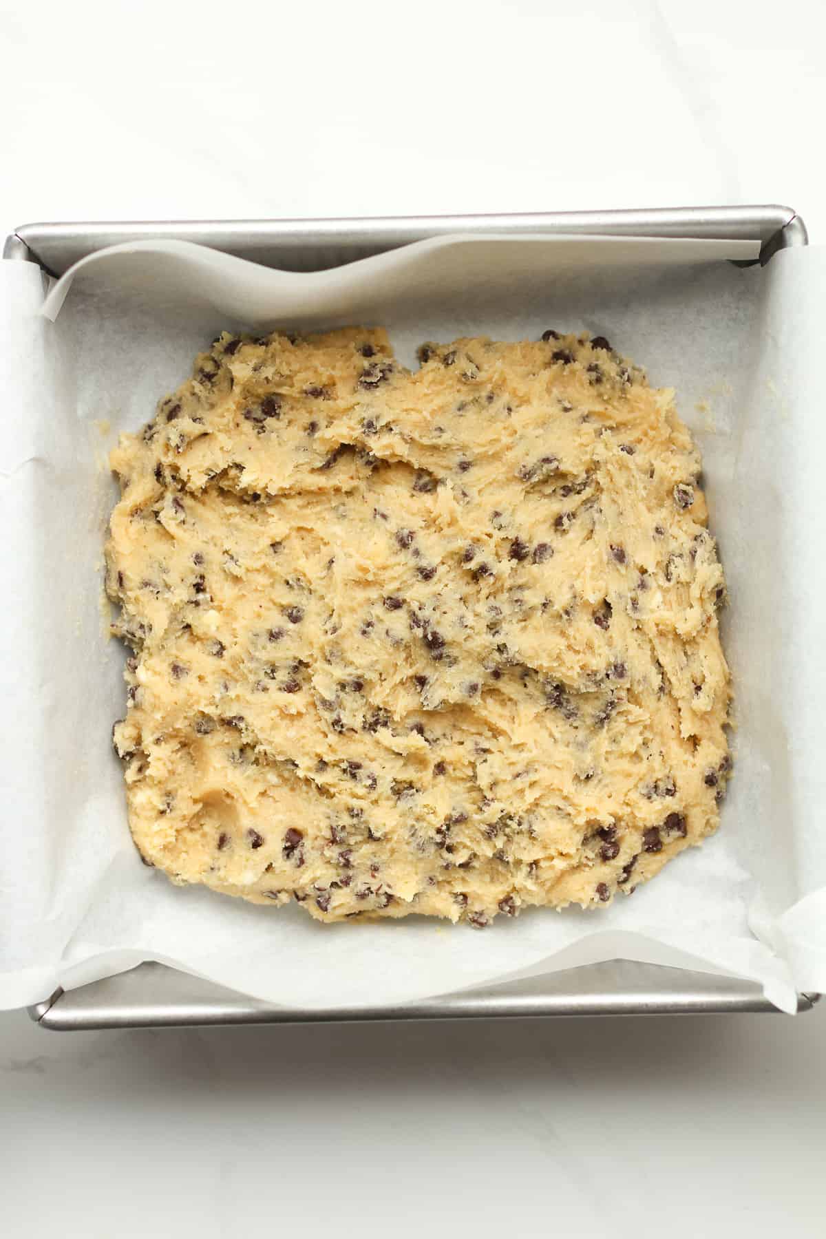 A square pan with the cookie batter inside (layer one).