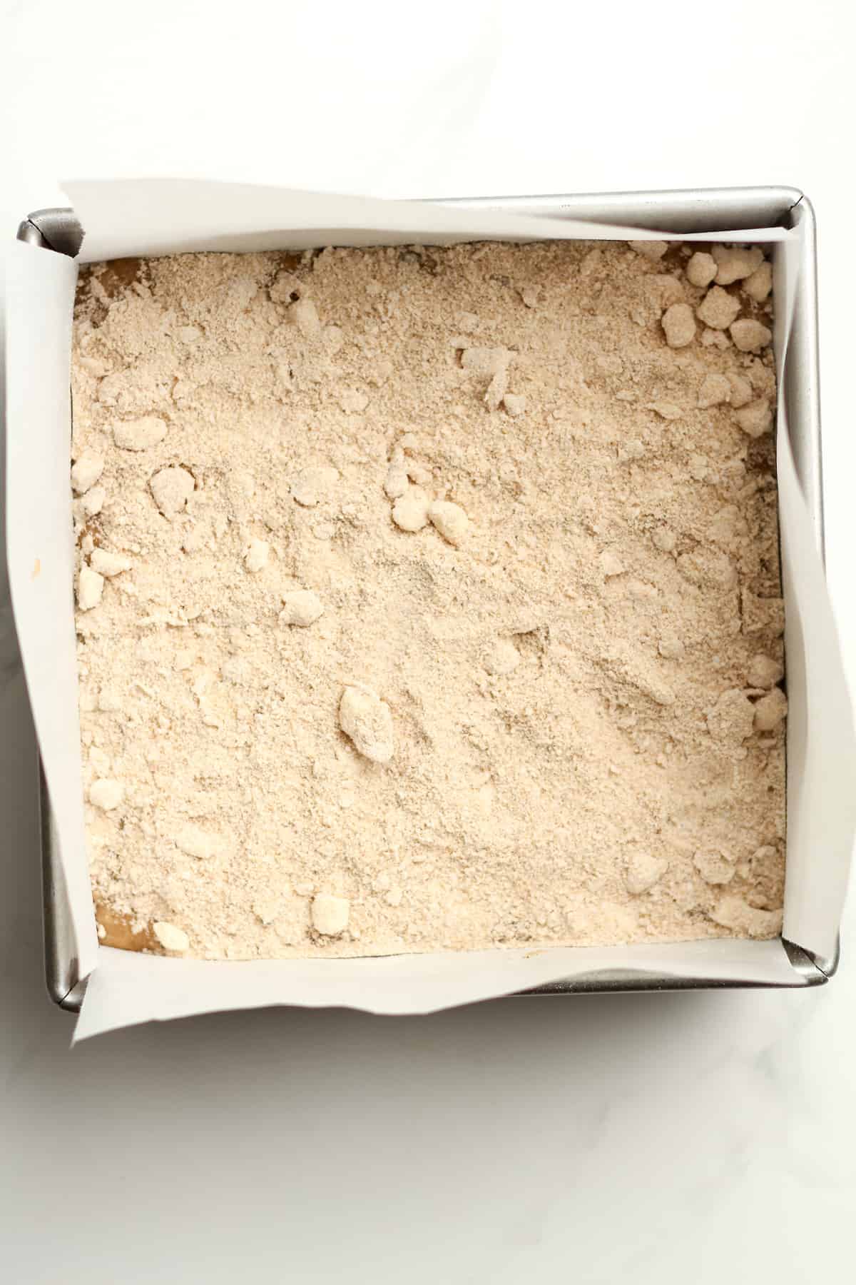 A square pan of the banana batter with the streusel topping on top.