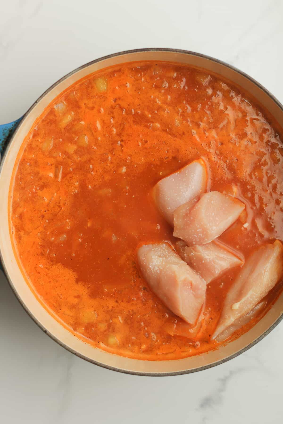 A stock pot with the raw chicken on top.