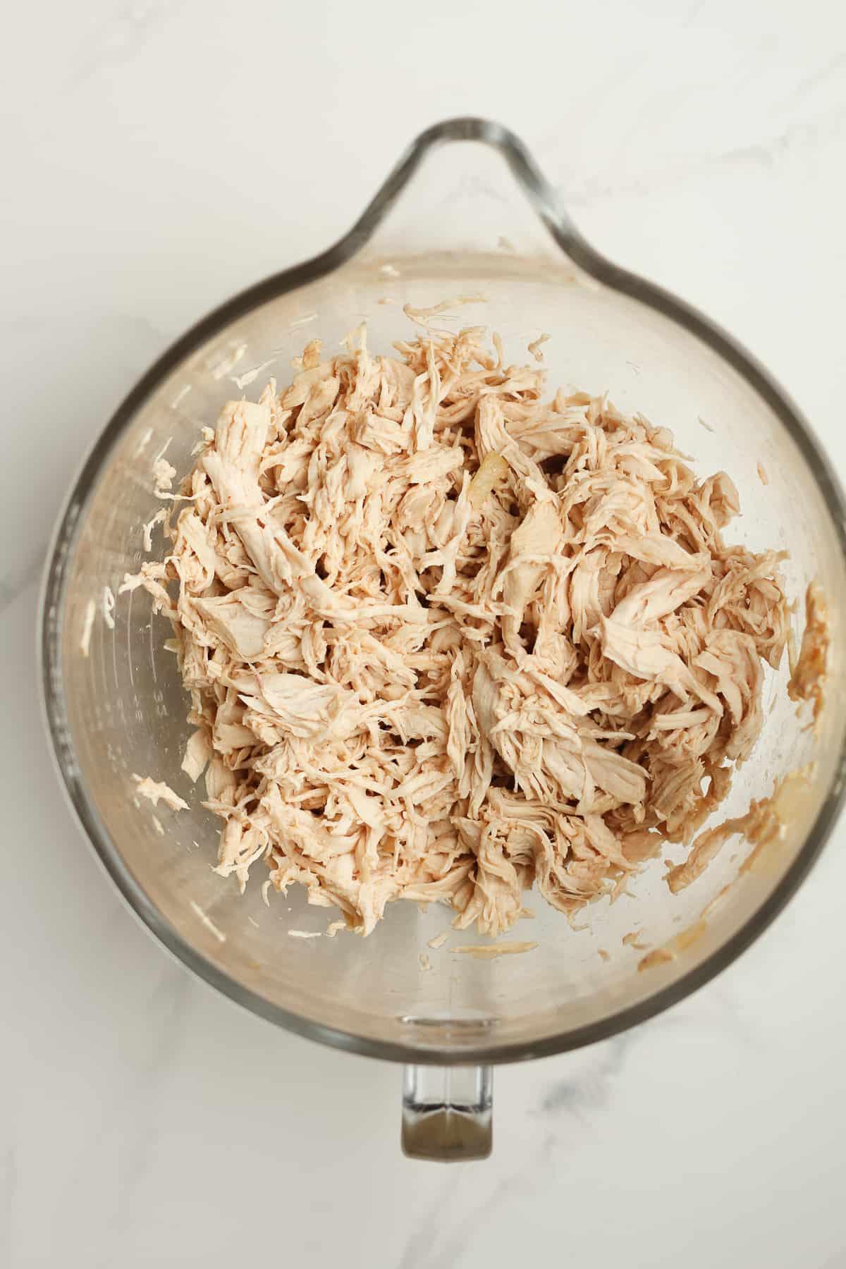 A mixing bowl with shredded chicken.