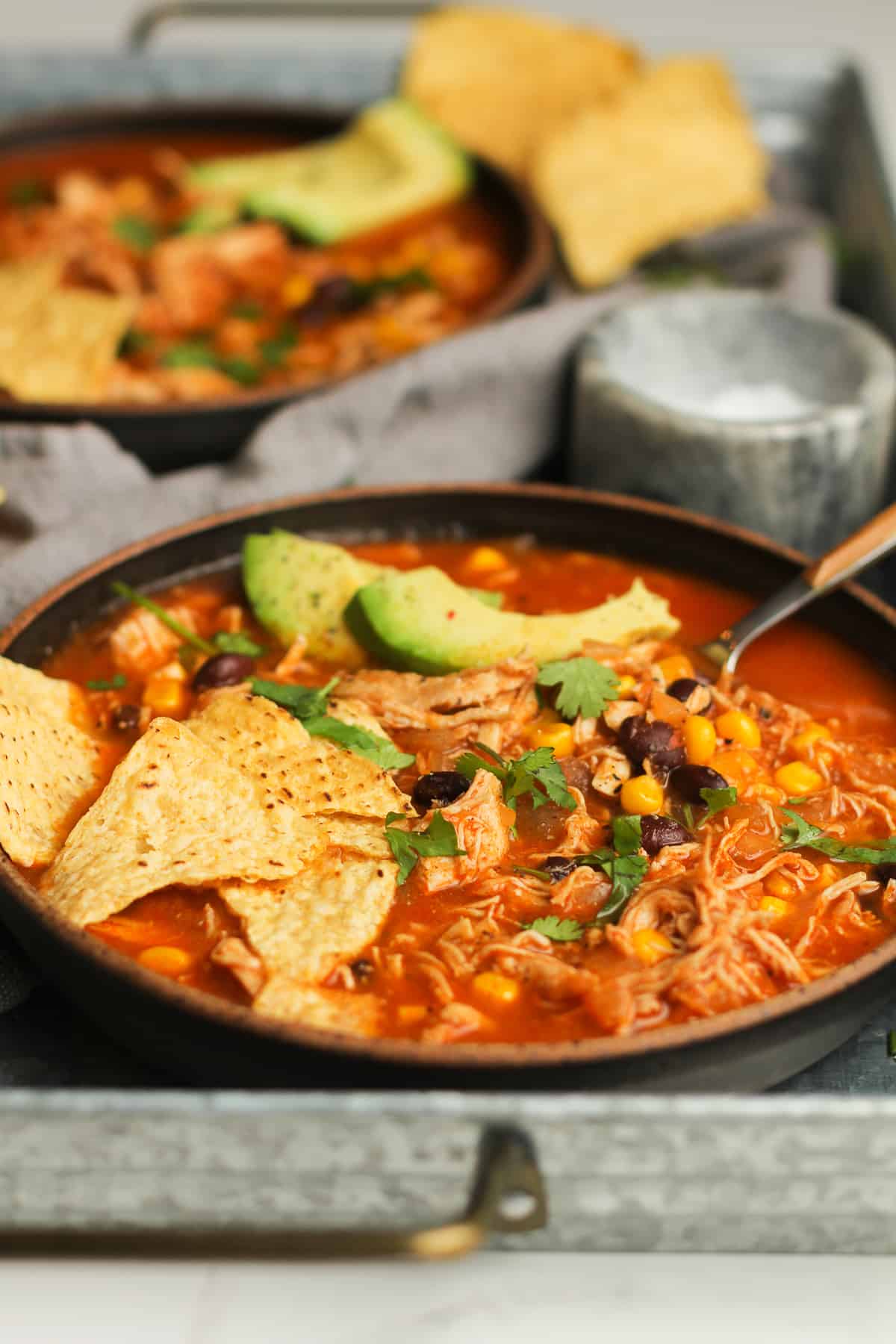Side view of two bowls of chicken tortilla soup.