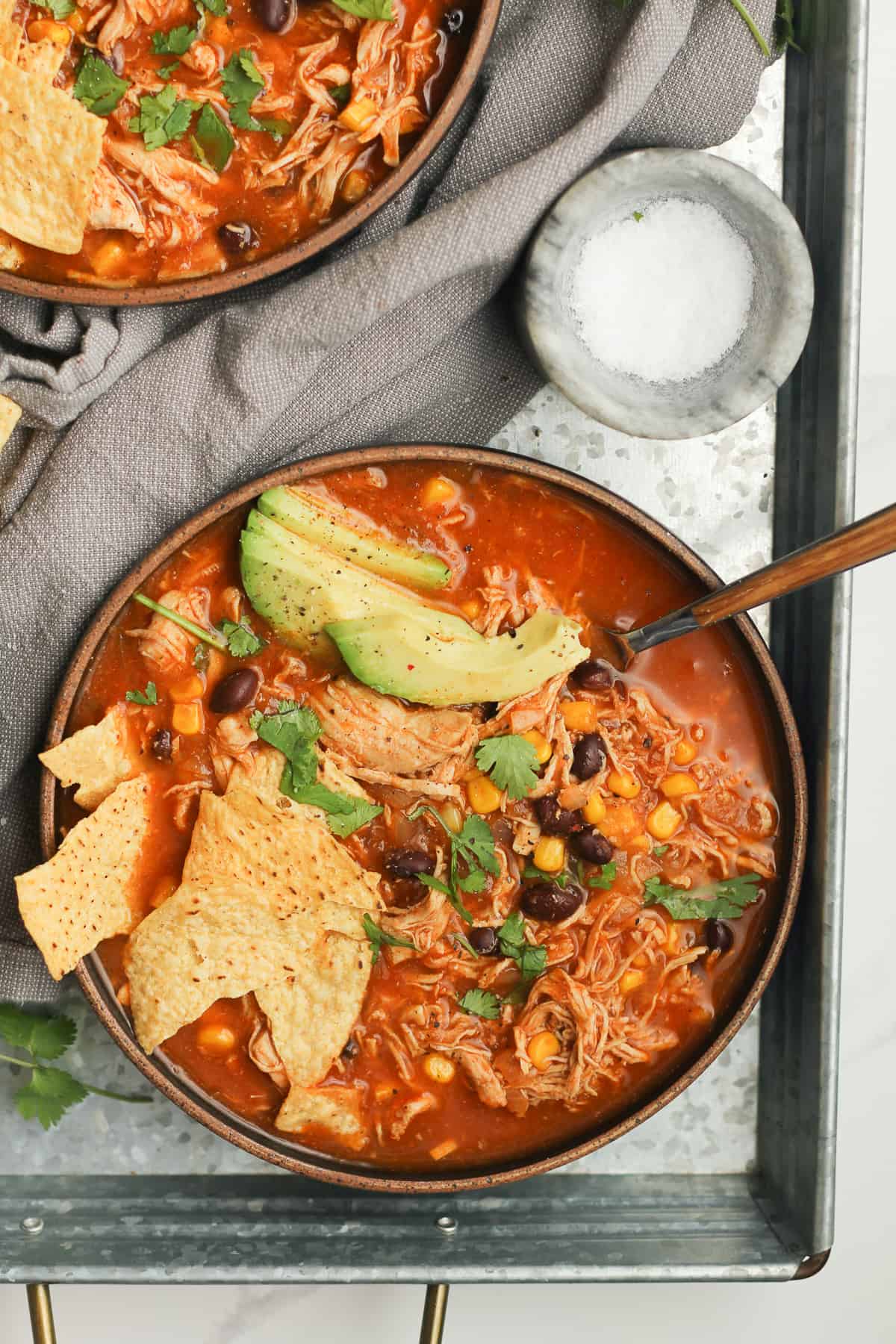 Two bowls of chicken tortilla soup on a gray tray.
