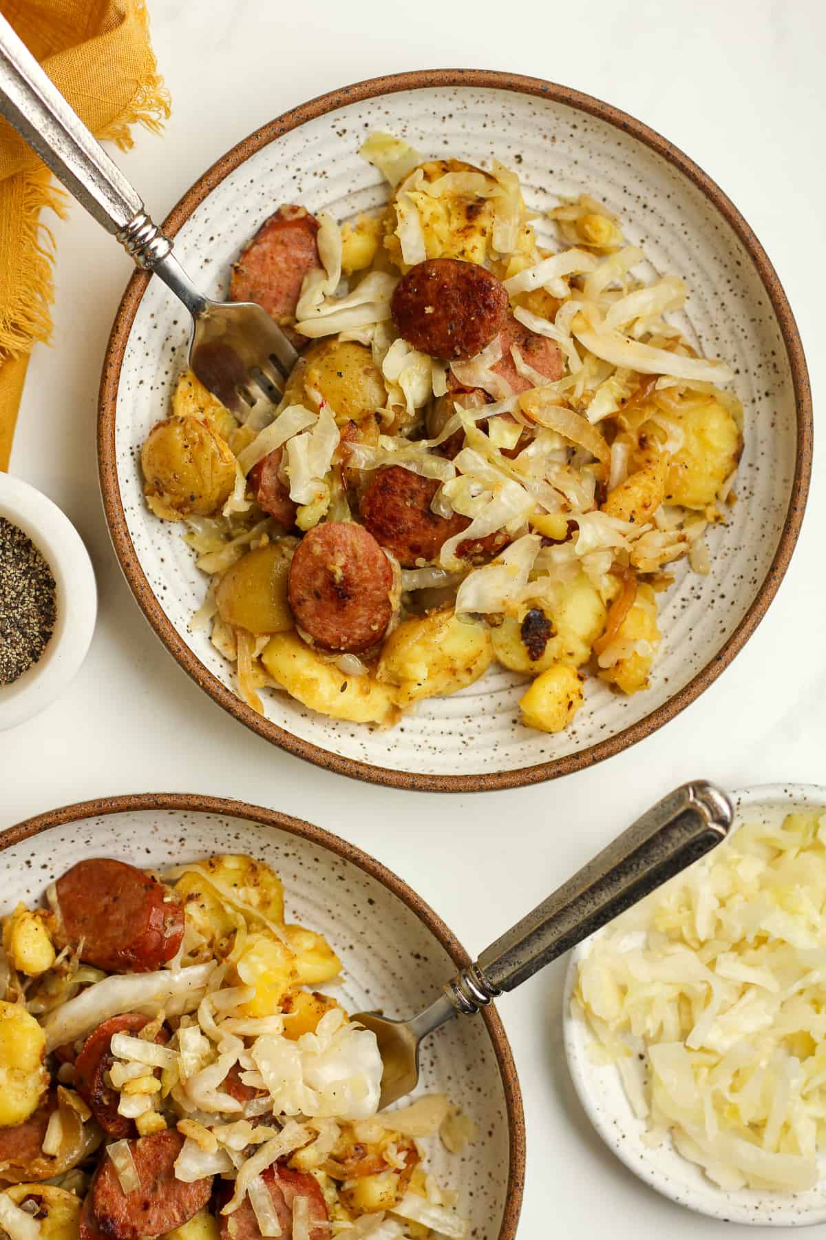Two bowls of the sausage and sauerkraut skillet, with forks.