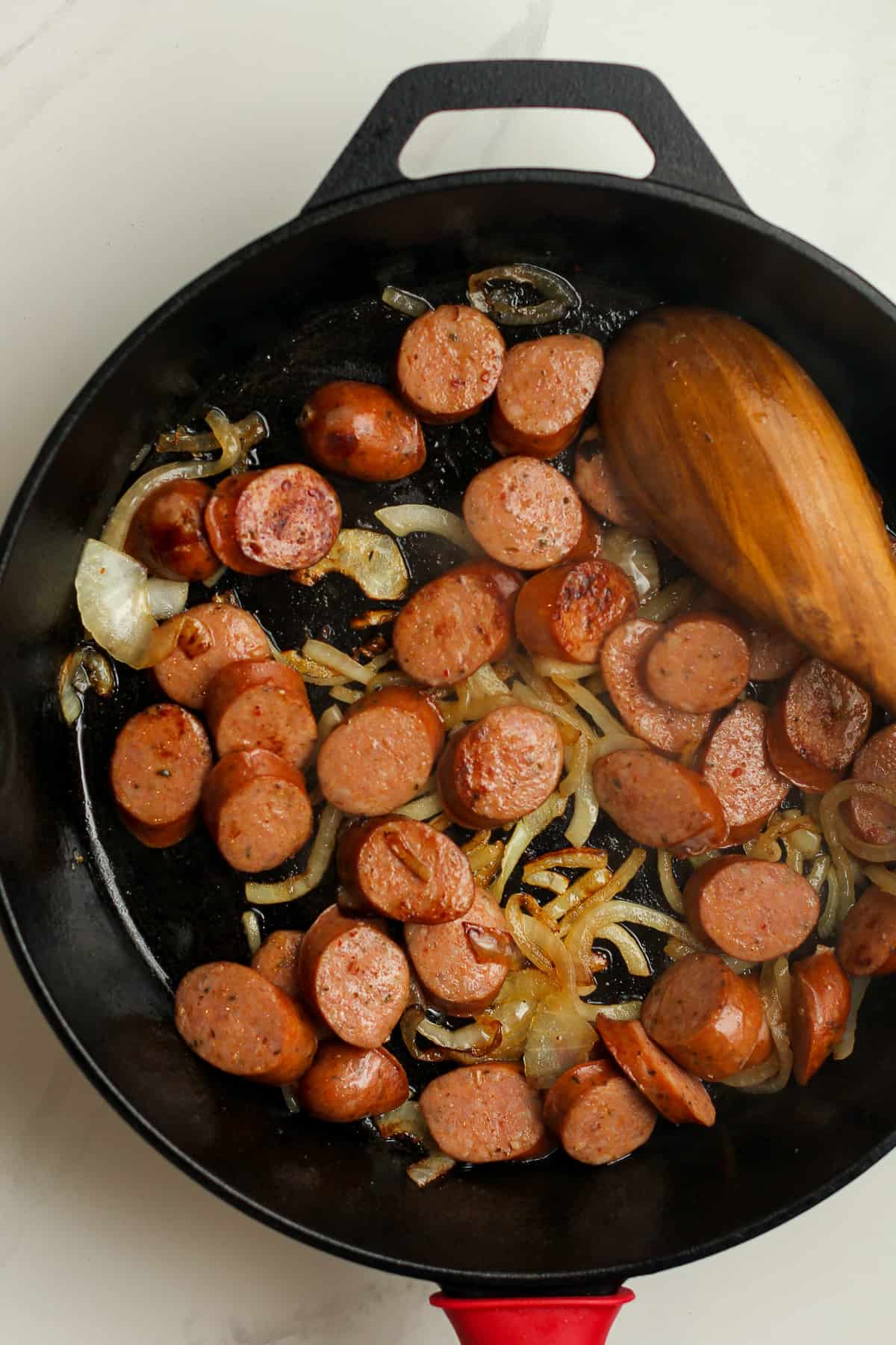 A skillet with the cooked sausage and onions.