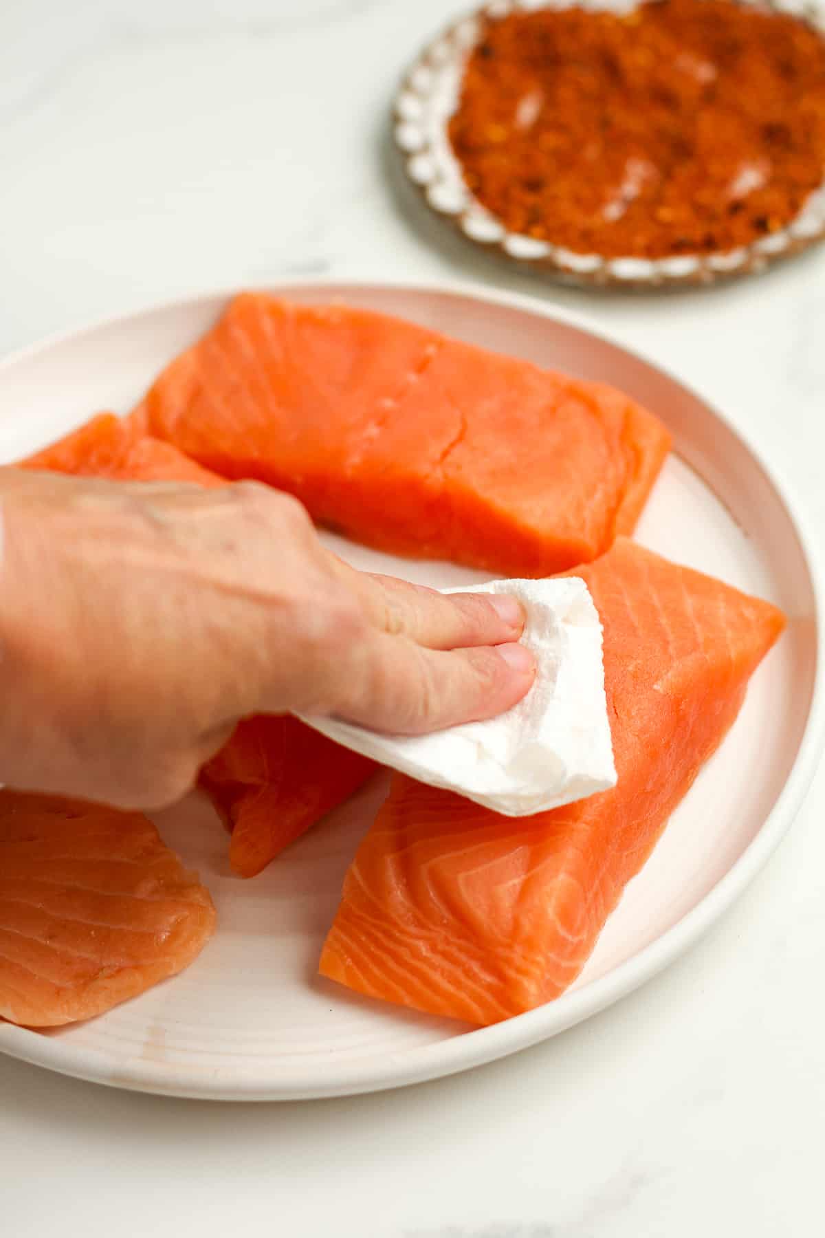 A hand drying off the salmon with paper towel.